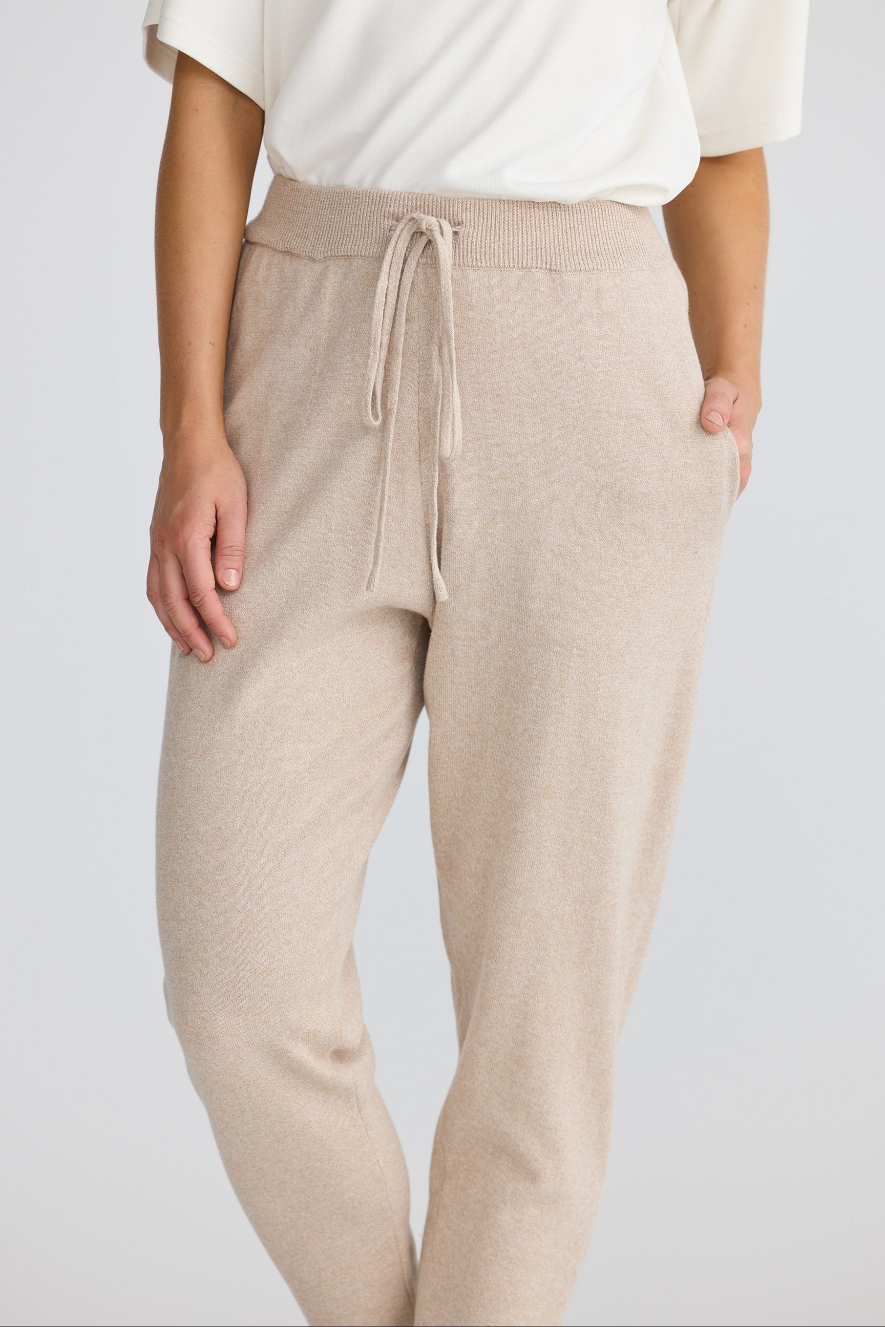 Beige pants with a drawstring waist worn by a person on a white background