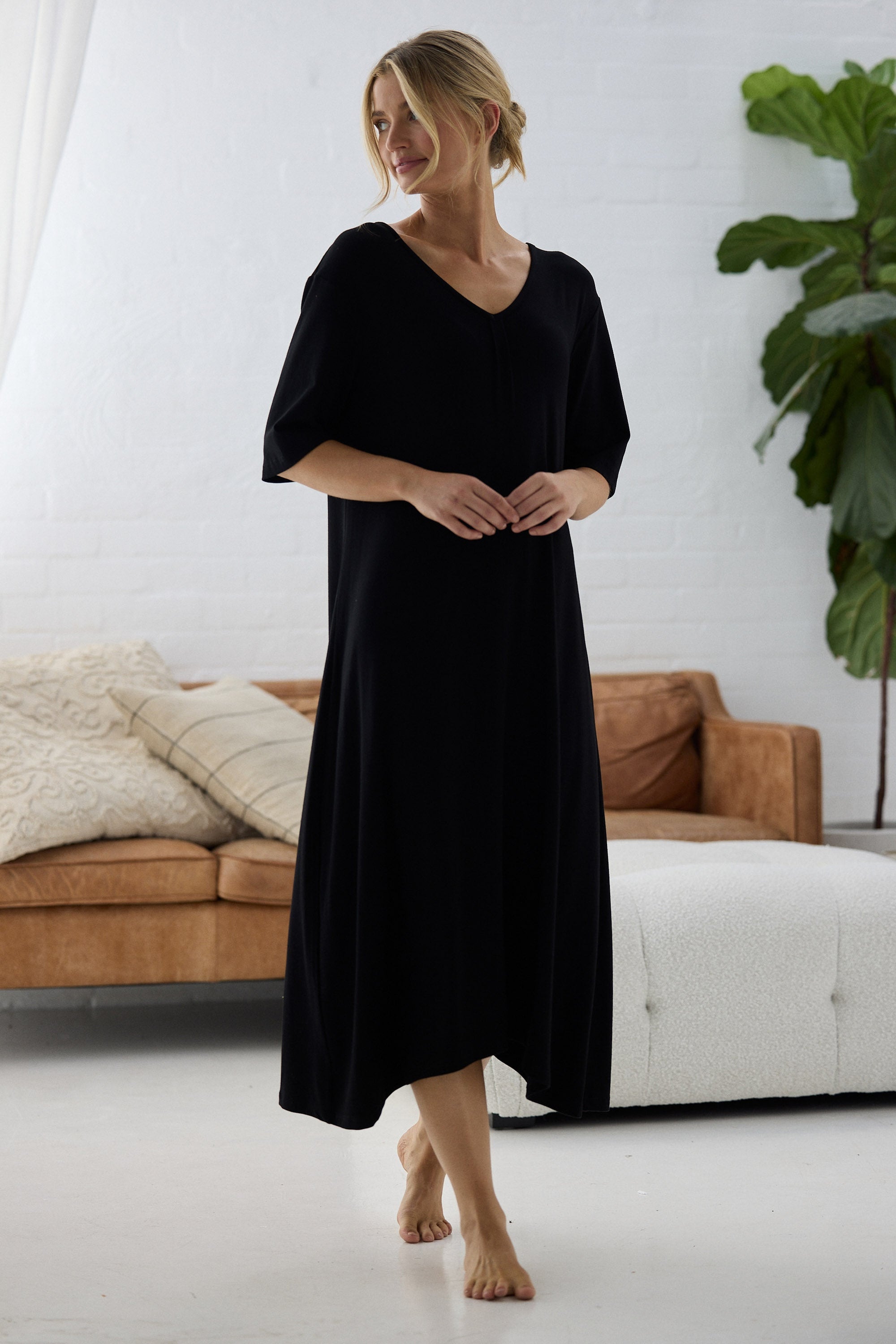 Woman wearing a black dress standing in a modern living room.