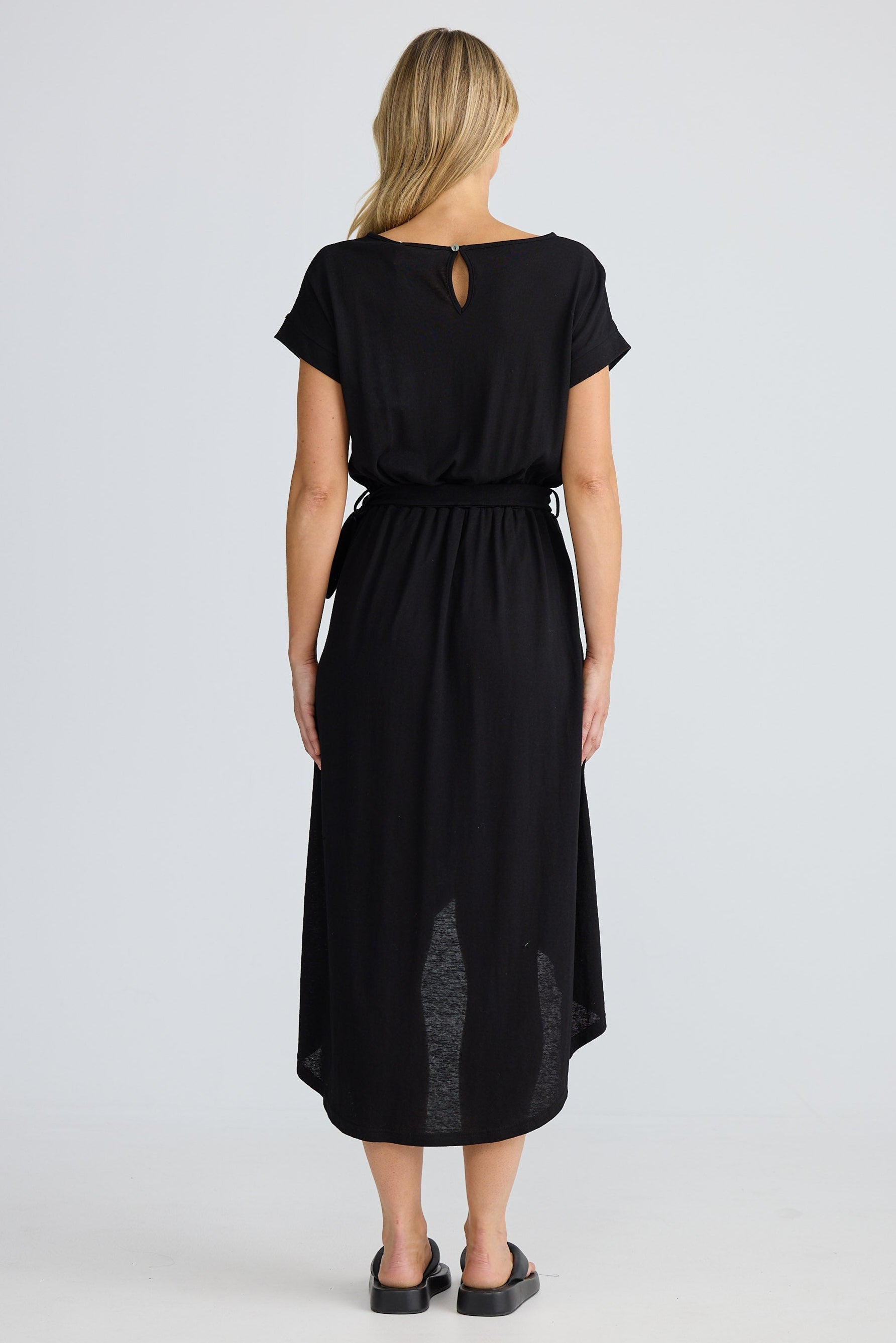 Woman wearing a black dress with a belt on a white background