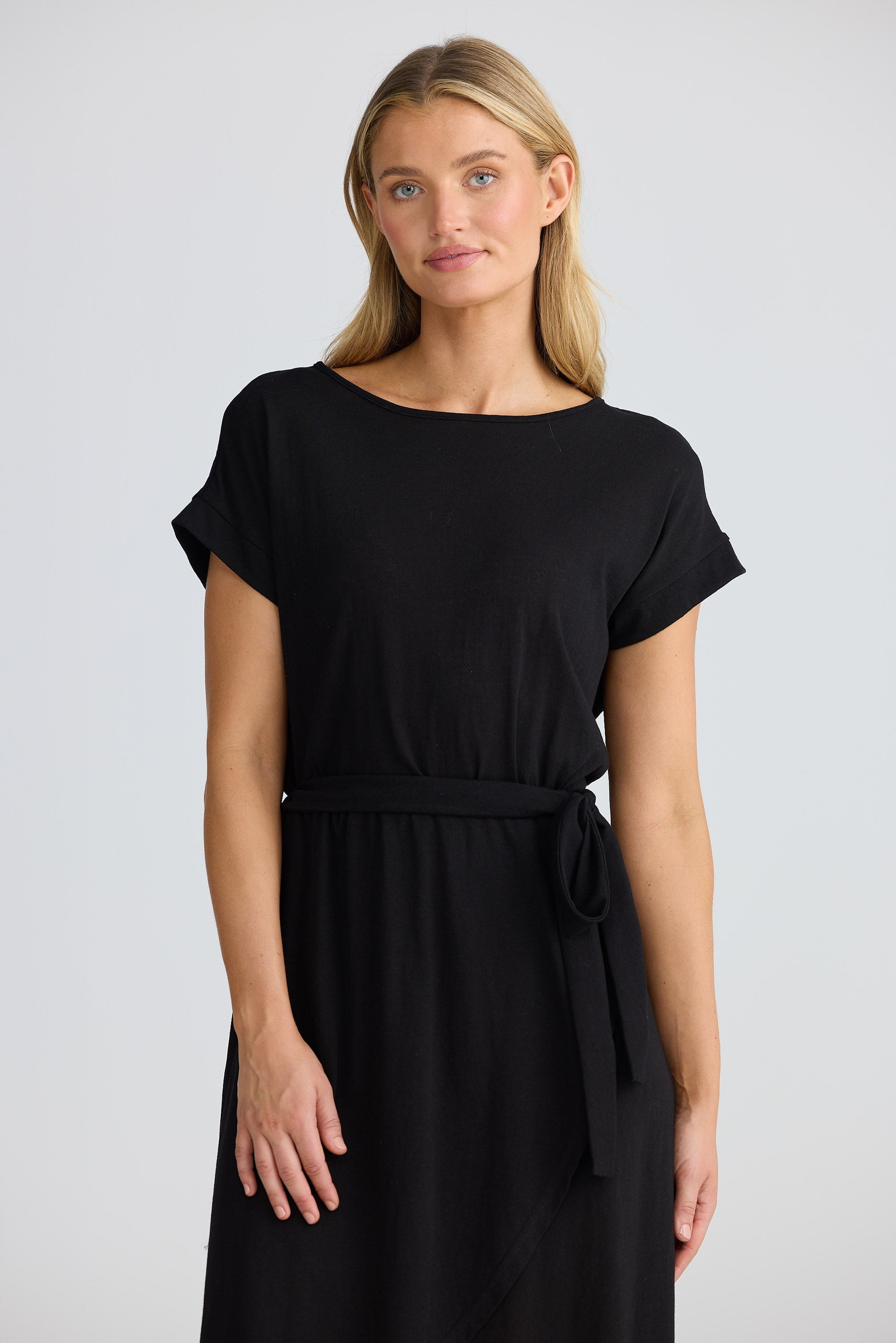 Woman wearing a black dress with a belt on a plain background