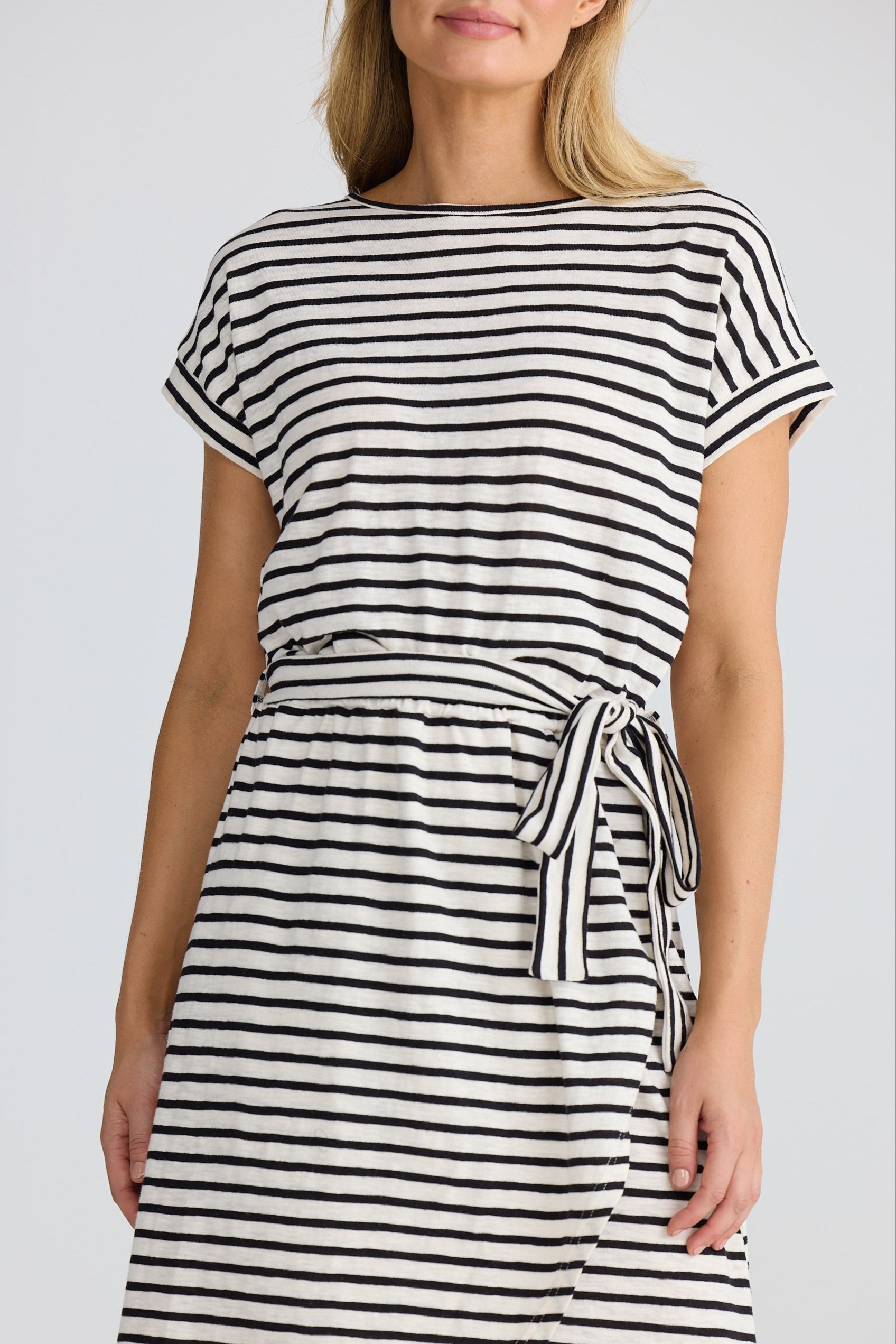 Woman wearing a black and white striped dress against a plain background