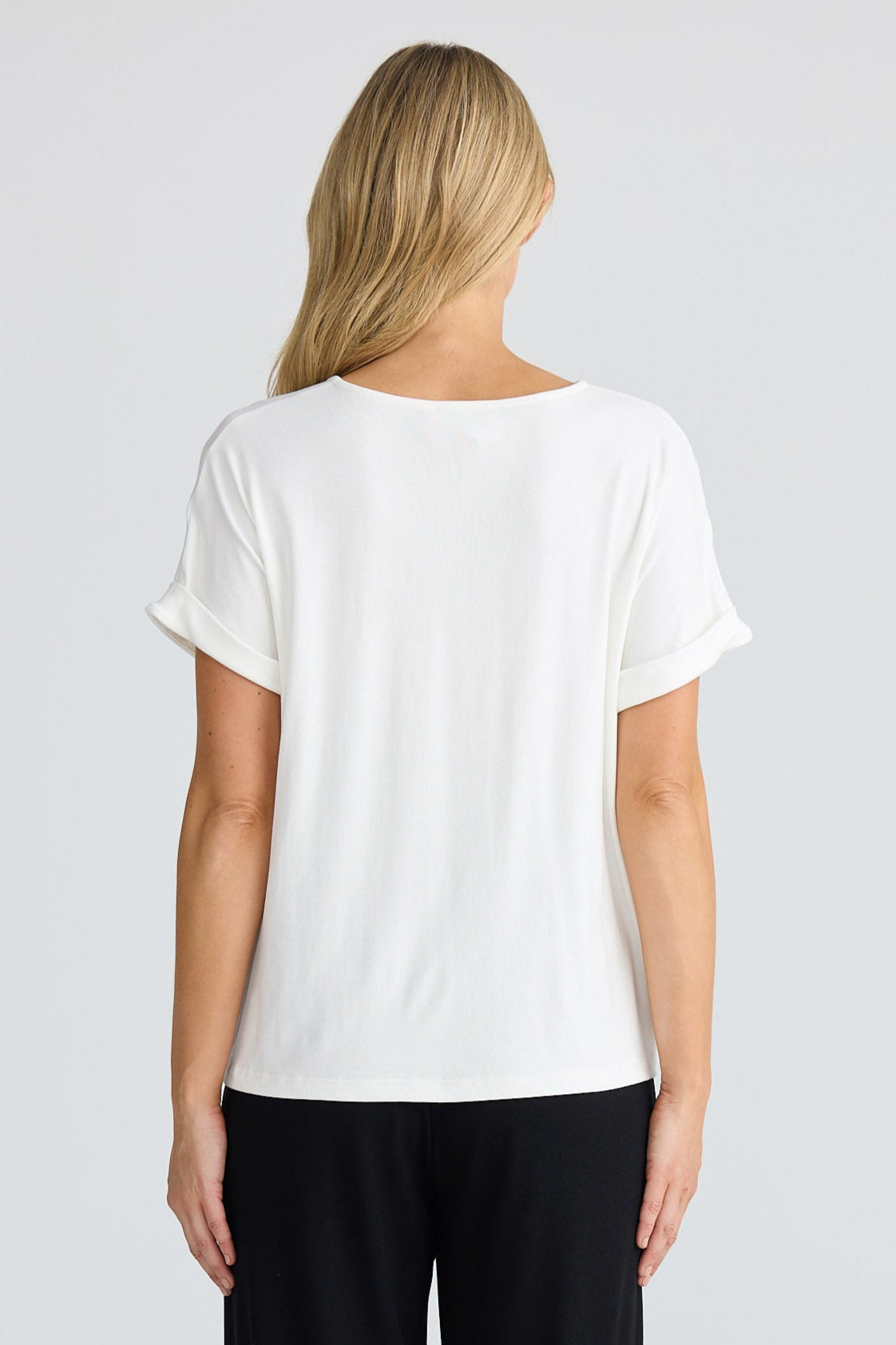 Person wearing a white t-shirt and black pants on a light gray background