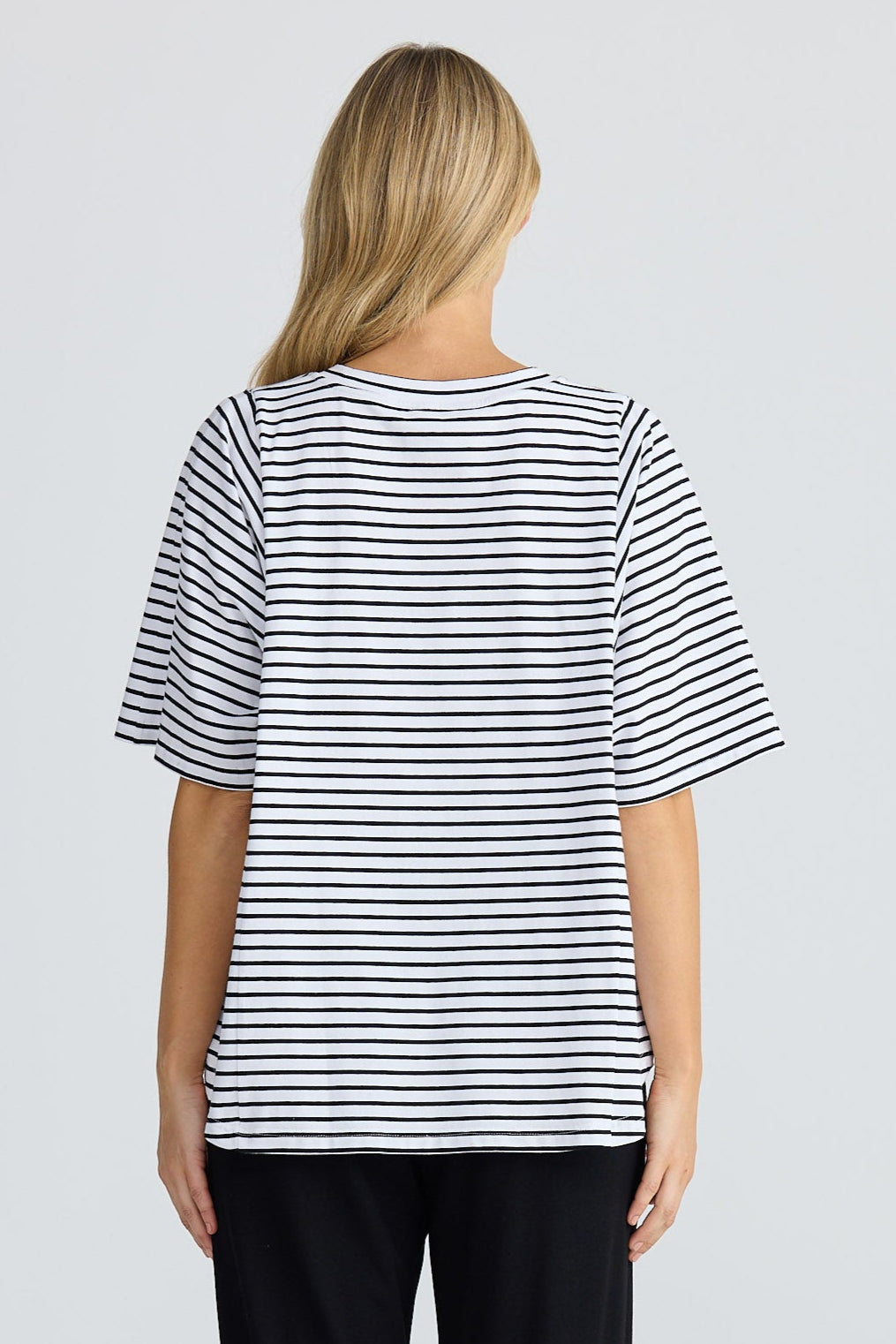 Person wearing a striped shirt and black pants on a white background