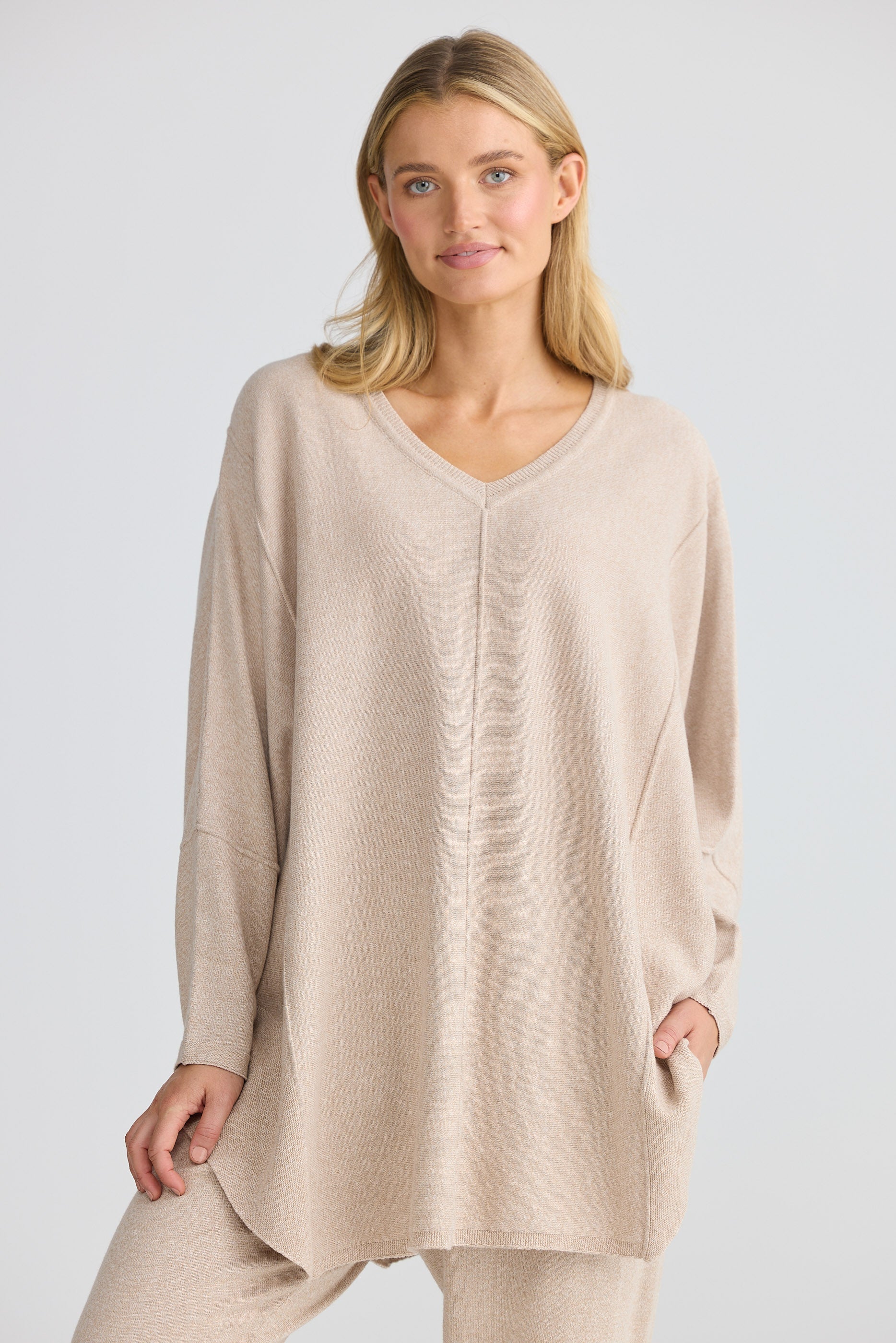 Woman wearing a beige long-sleeve top and pants on a white background