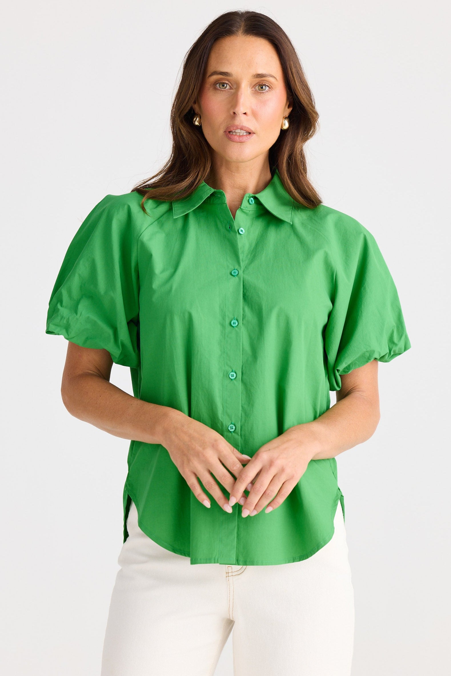 Woman wearing a green blouse and white pants on a white background