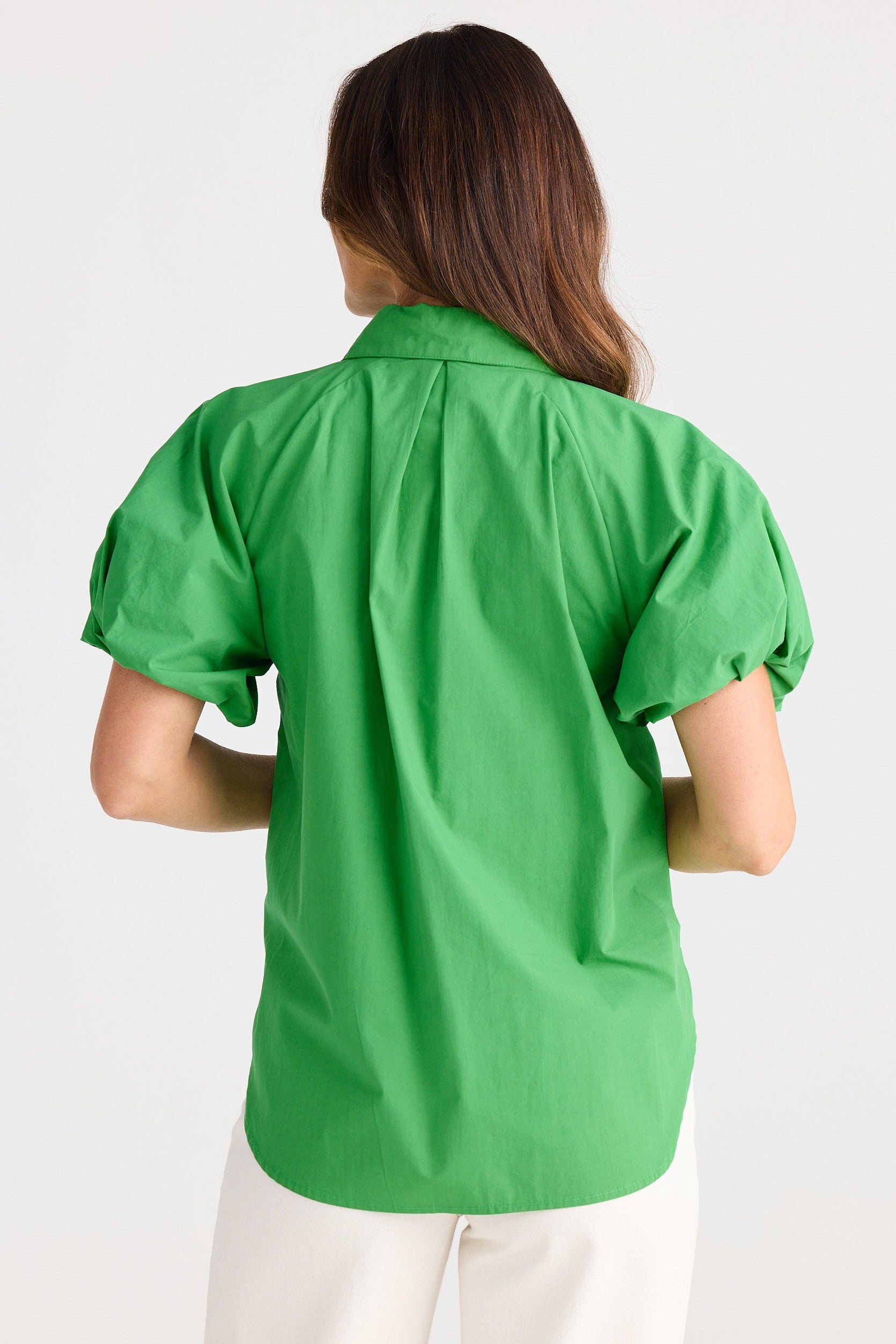 Person wearing a green blouse with puff sleeves on a white background
