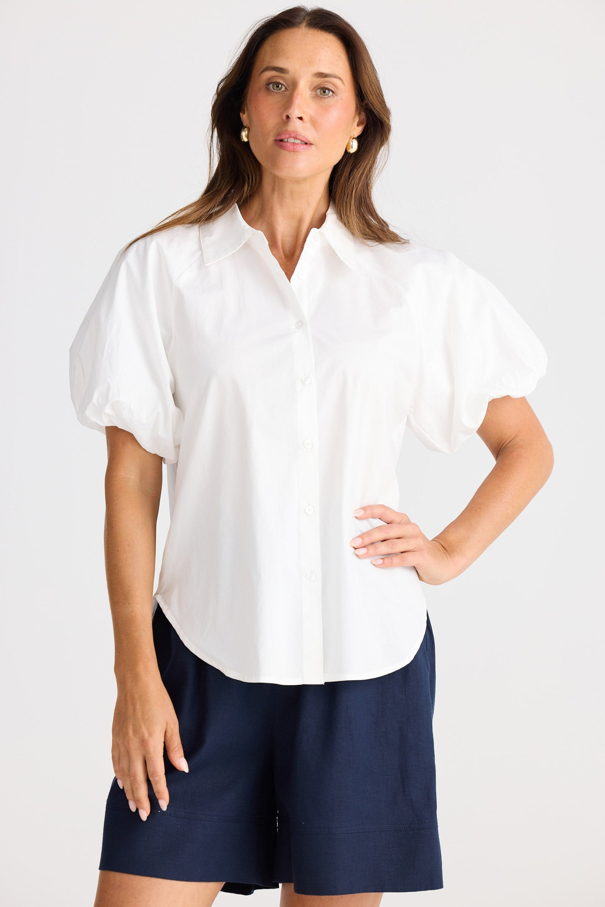 Woman wearing a white blouse and navy shorts on a white background