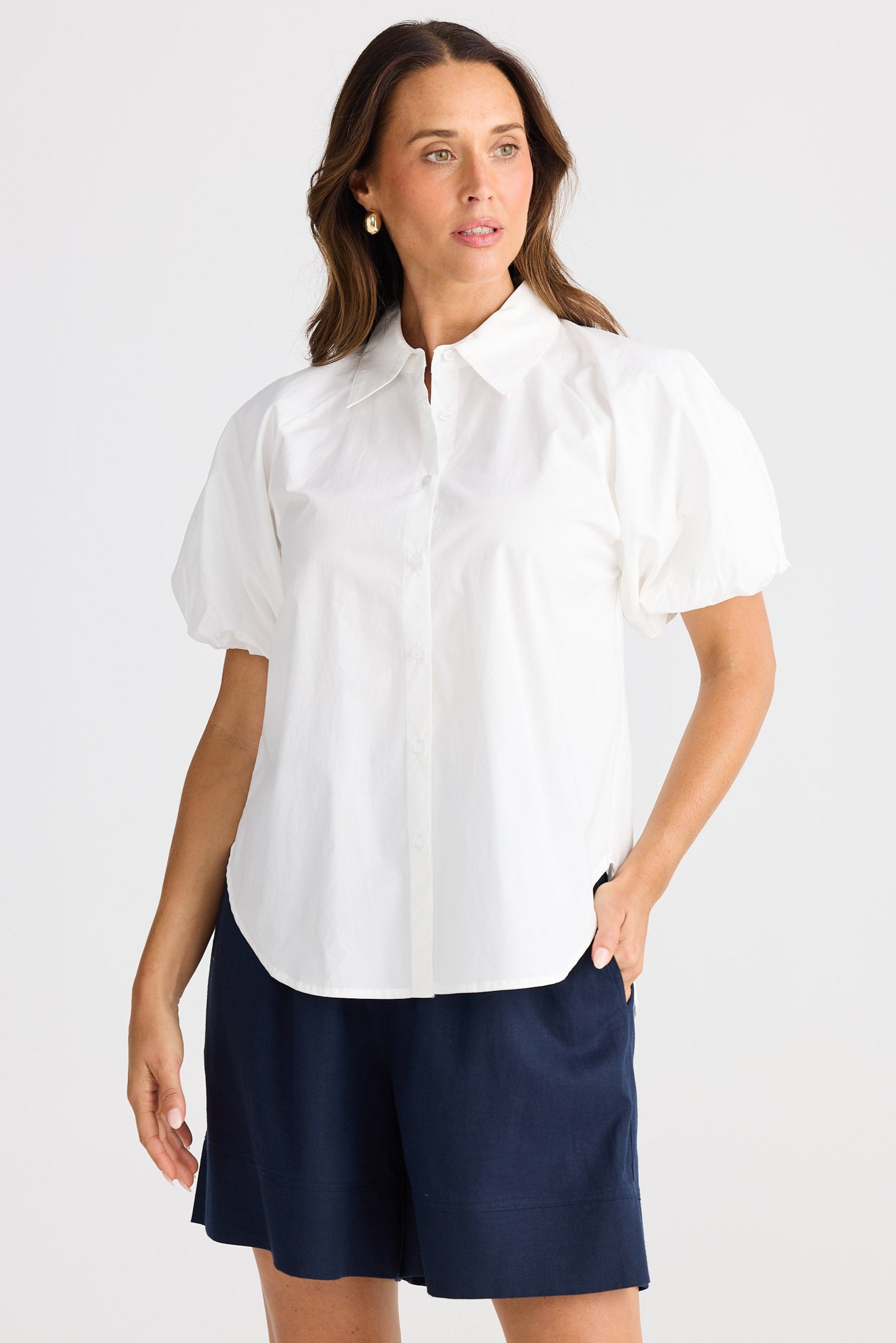 Woman wearing a white blouse and navy shorts on a white background