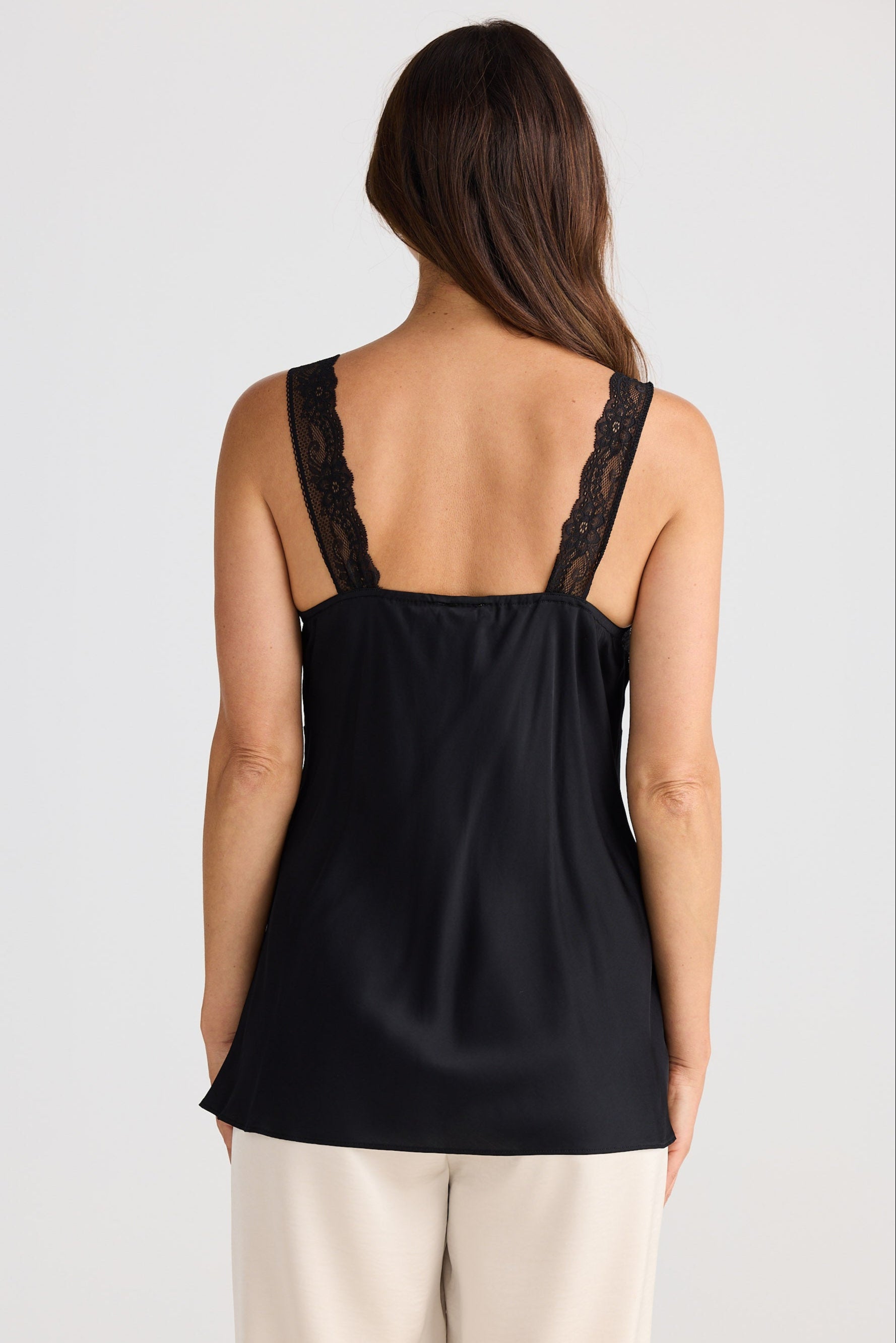 Woman wearing a black tank top with lace details on a white background