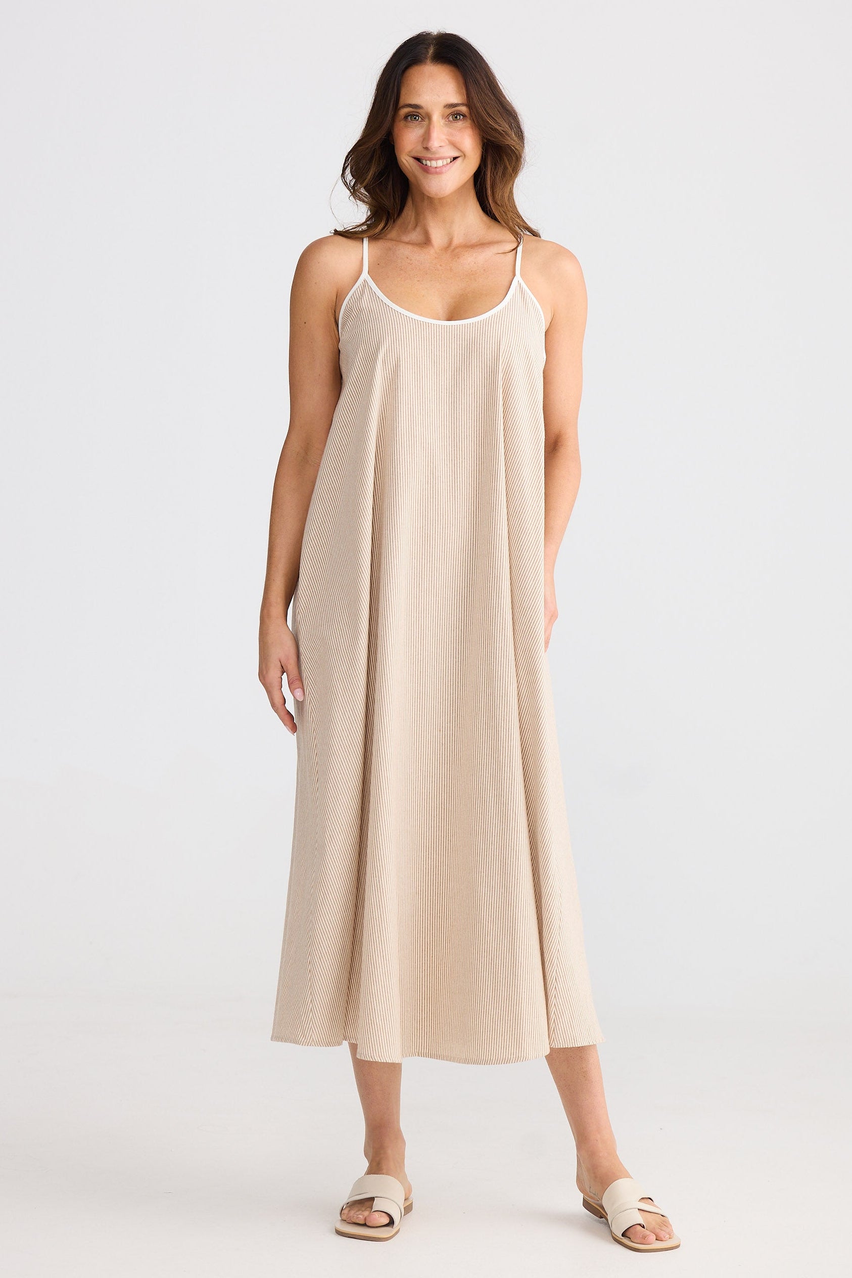 Woman wearing sleeveless beige striped dress on white background