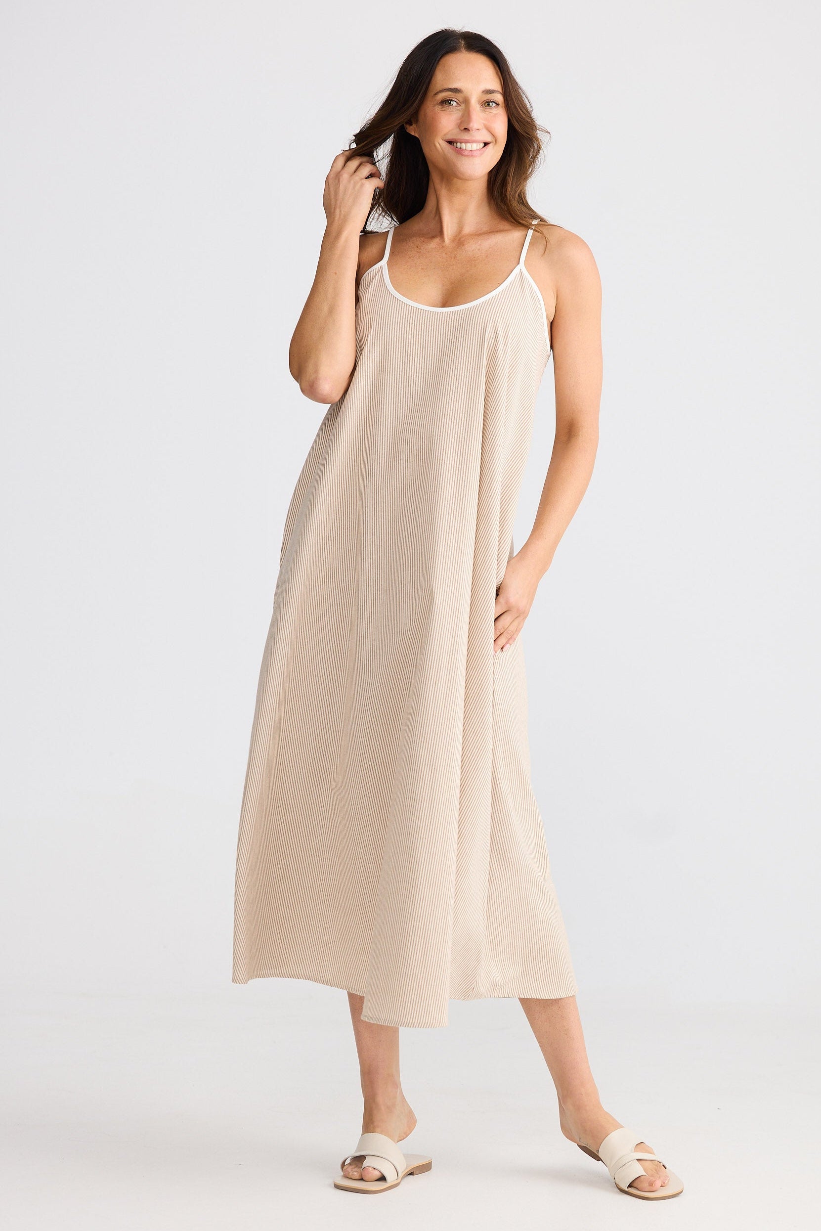 Woman wearing sleeveless beige striped dress on white background