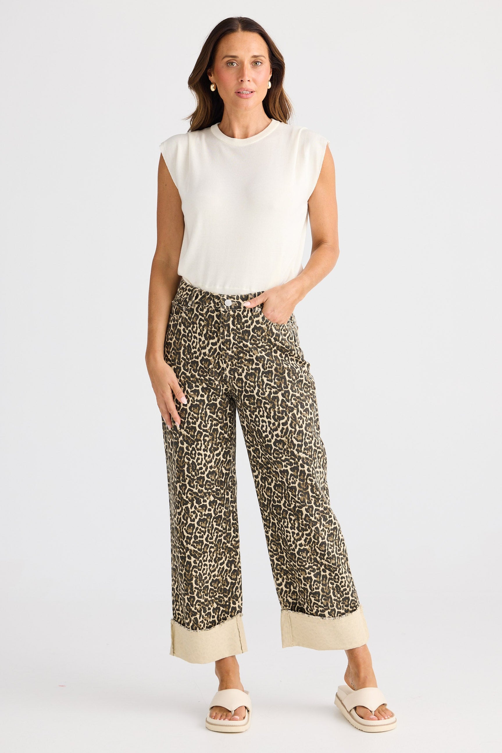 Woman wearing a white sleeveless top and patterned pants on a white background