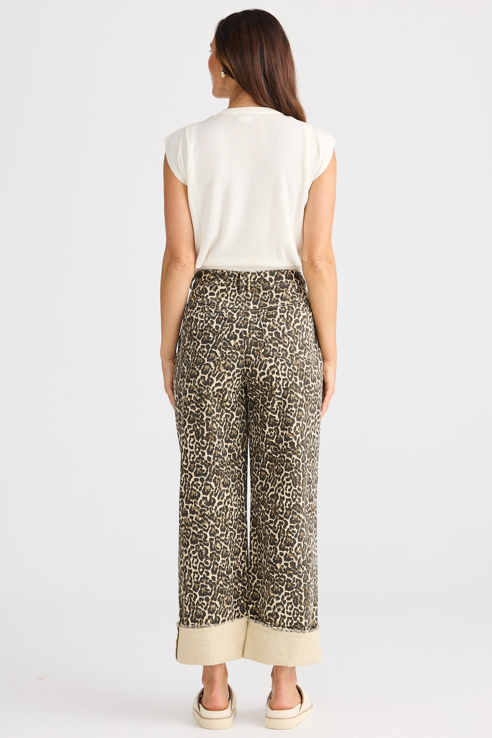 Woman wearing a white top and patterned pants on a white background