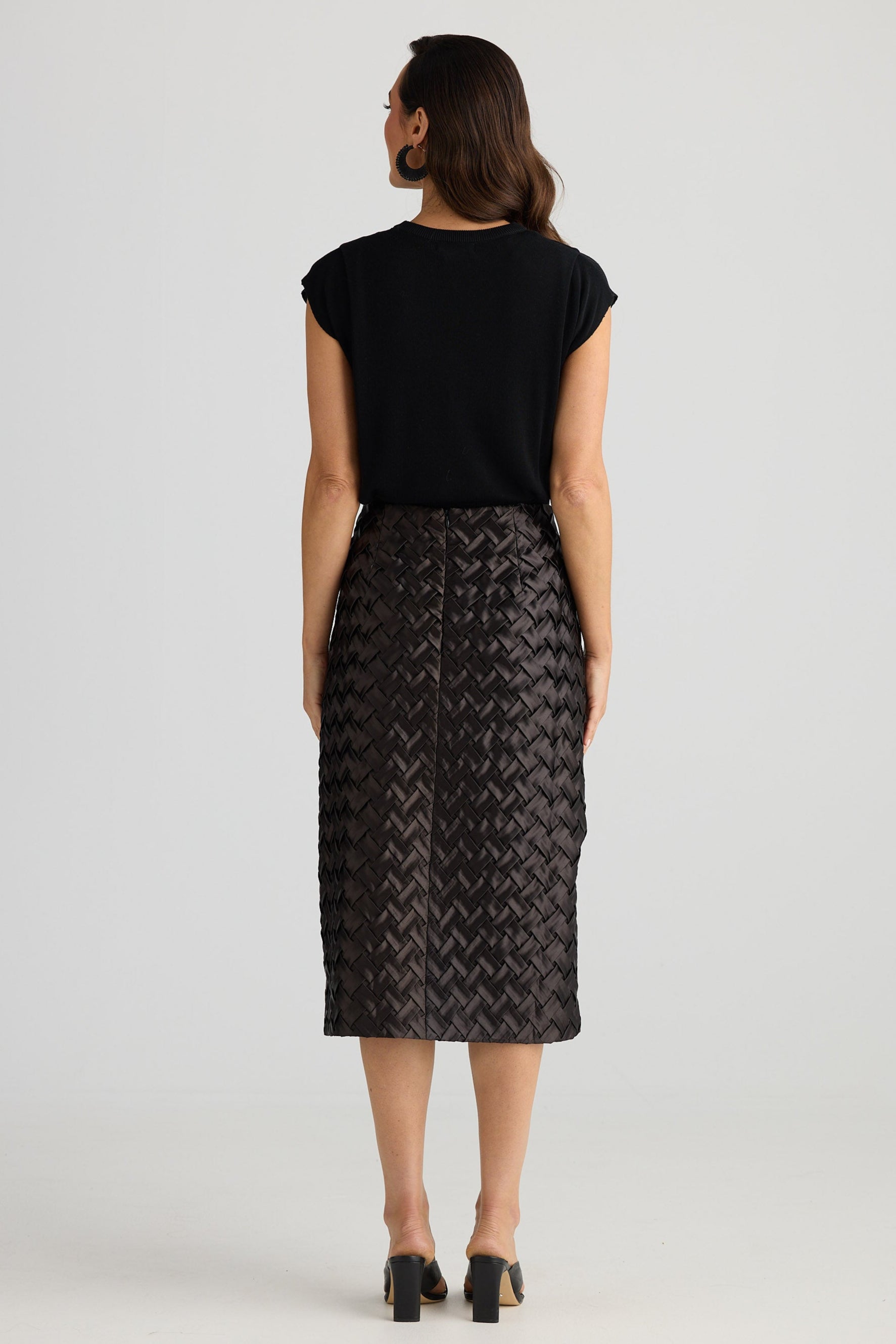 Woman wearing a black top and patterned skirt on a white background