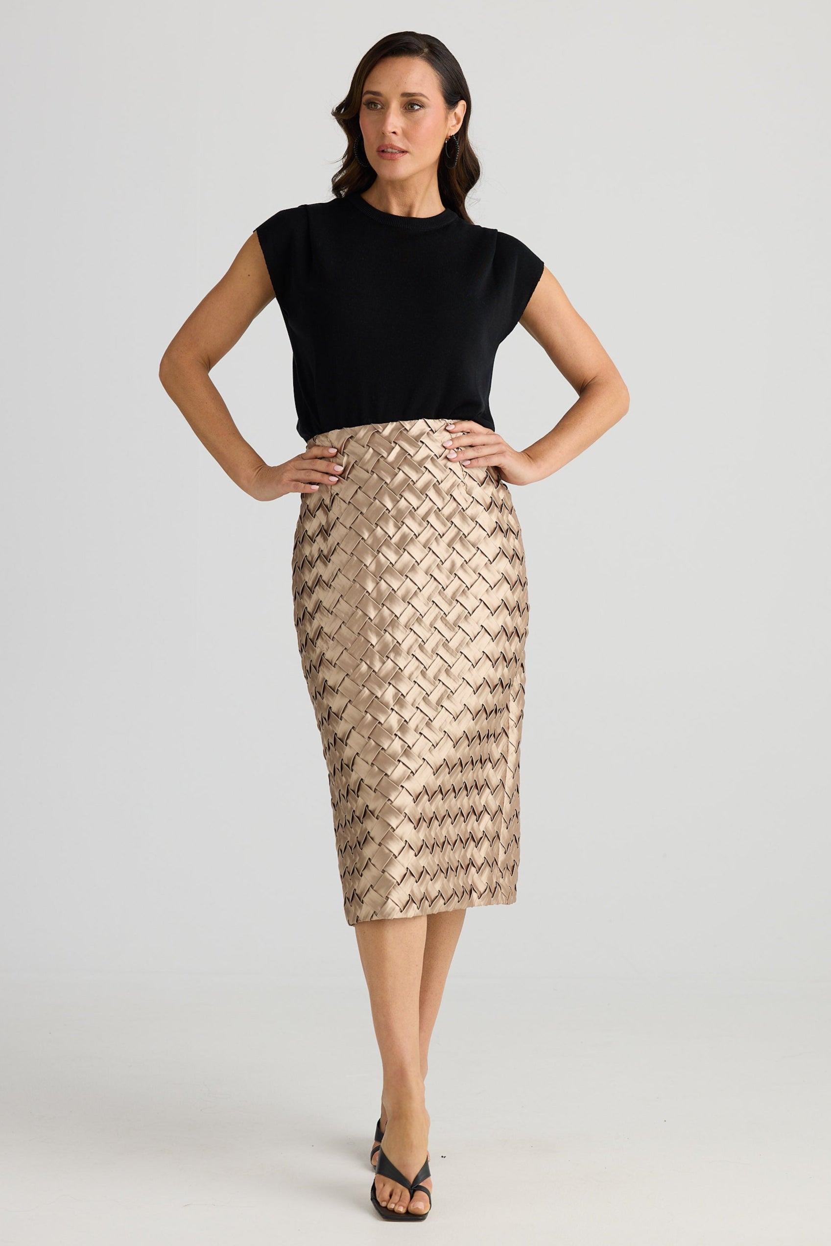 Woman wearing a black top and patterned skirt on a white background