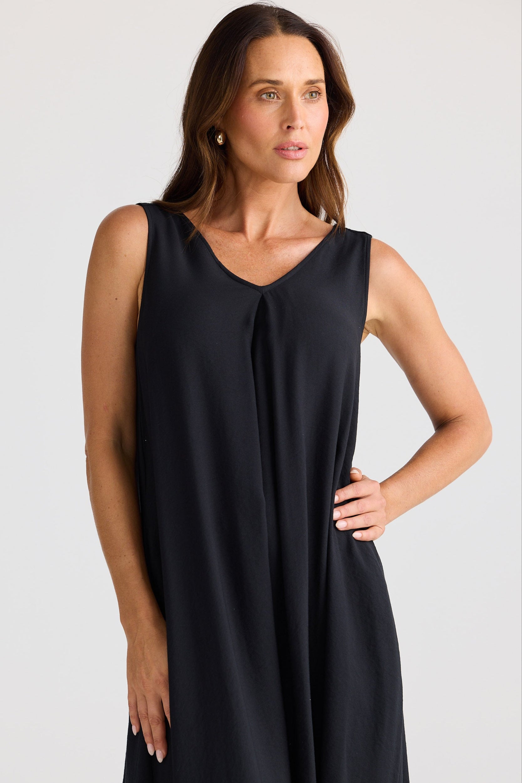 Woman wearing a black sleeveless dress against a plain background