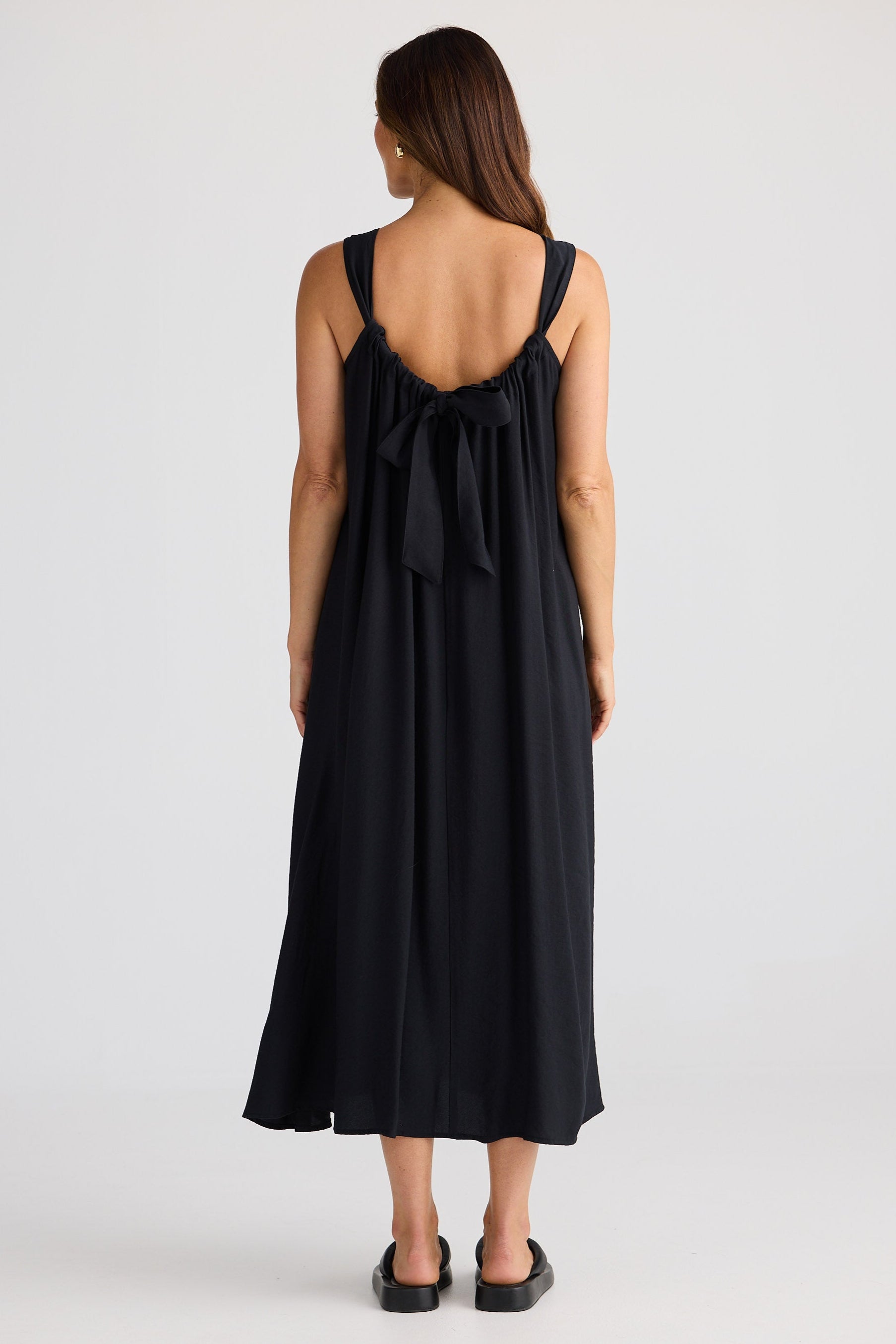 Woman wearing a black dress with a bow detail on a white background