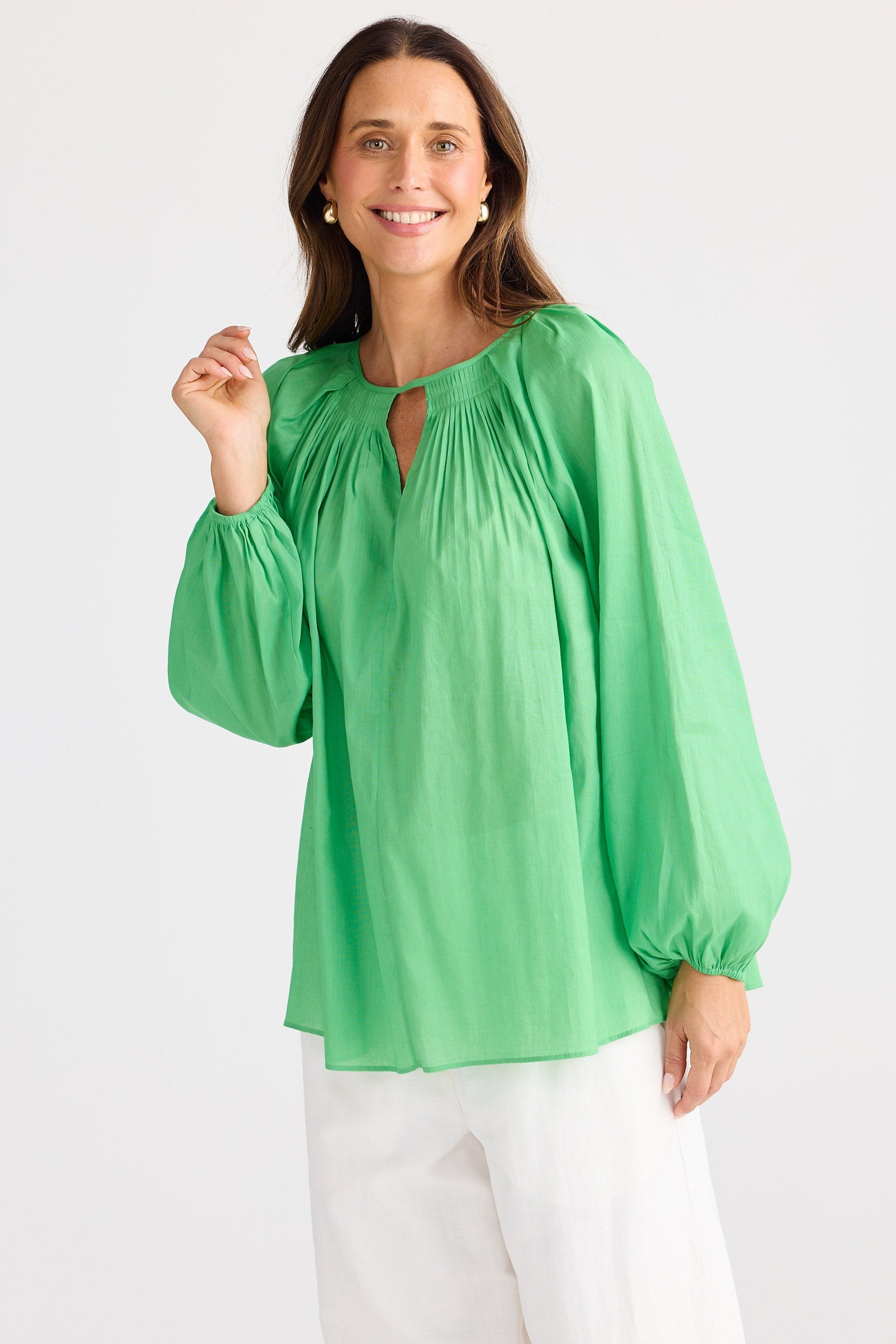 Woman wearing a green blouse with long sleeves on a white background