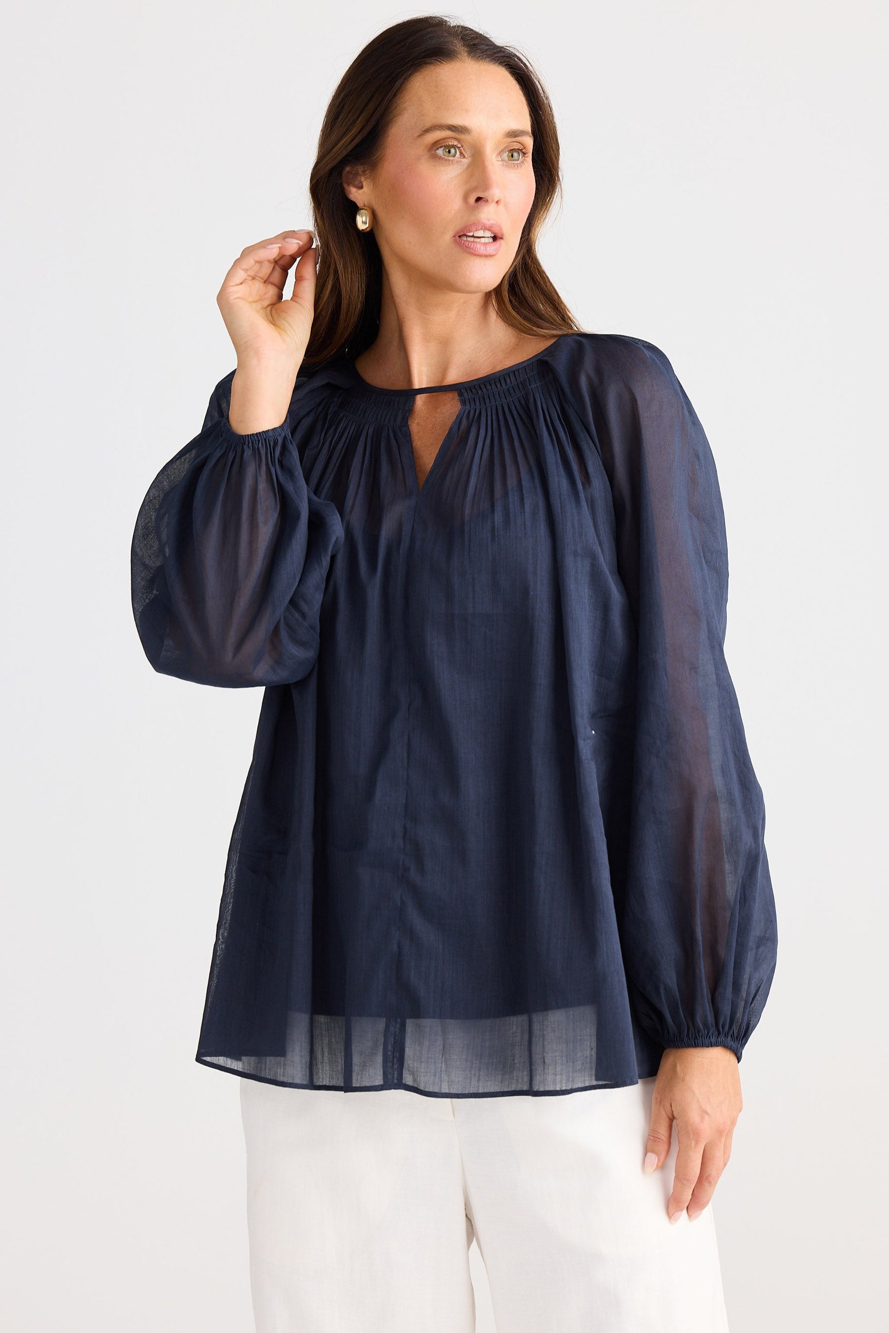 Woman wearing a navy blue blouse with long sleeves on a white background