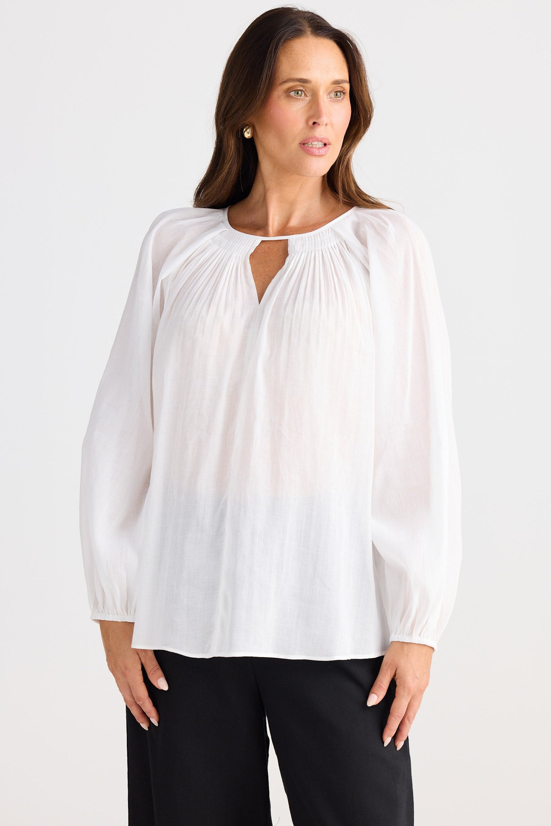 Woman wearing a white blouse with a cut-out design on a white background