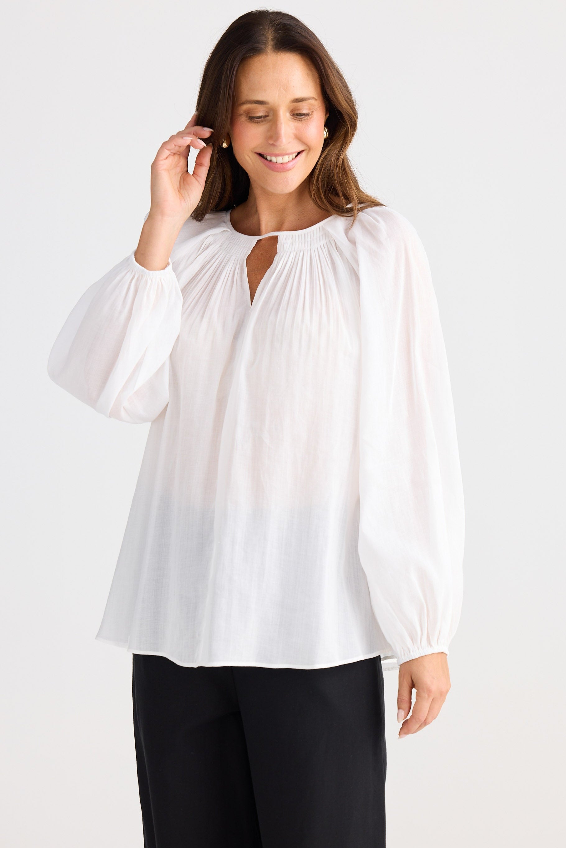 Woman wearing a white blouse with long sleeves on a plain background