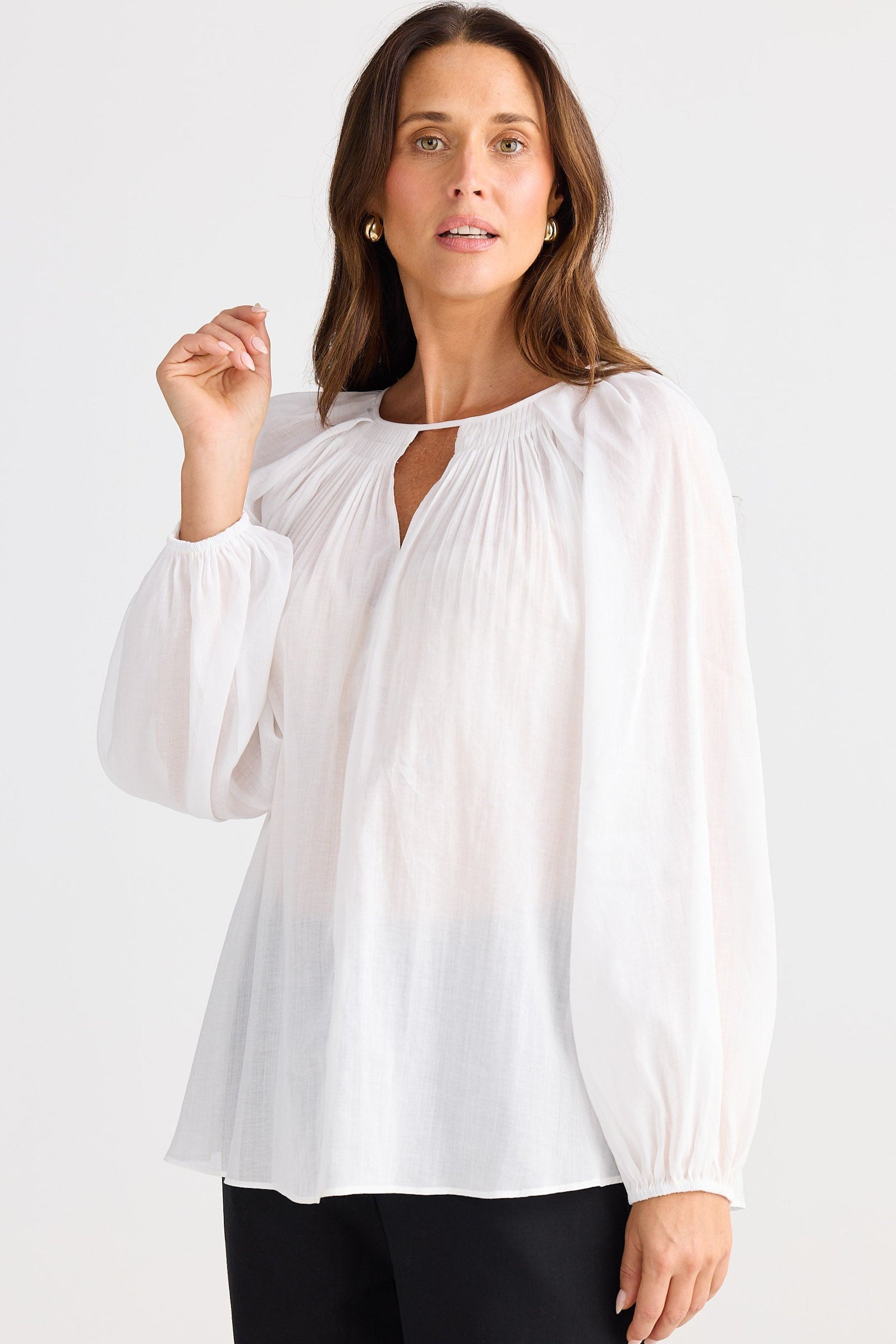 Woman wearing a white blouse with long sleeves on a white background