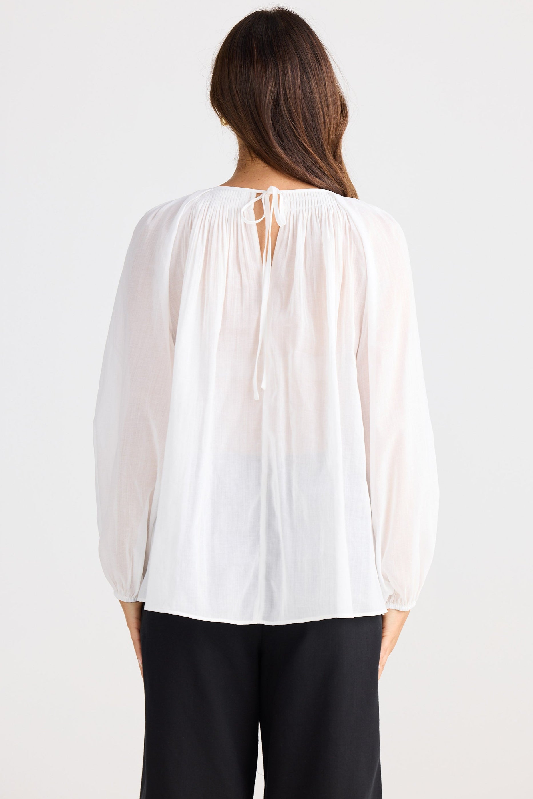 Woman wearing a white blouse with a plain background