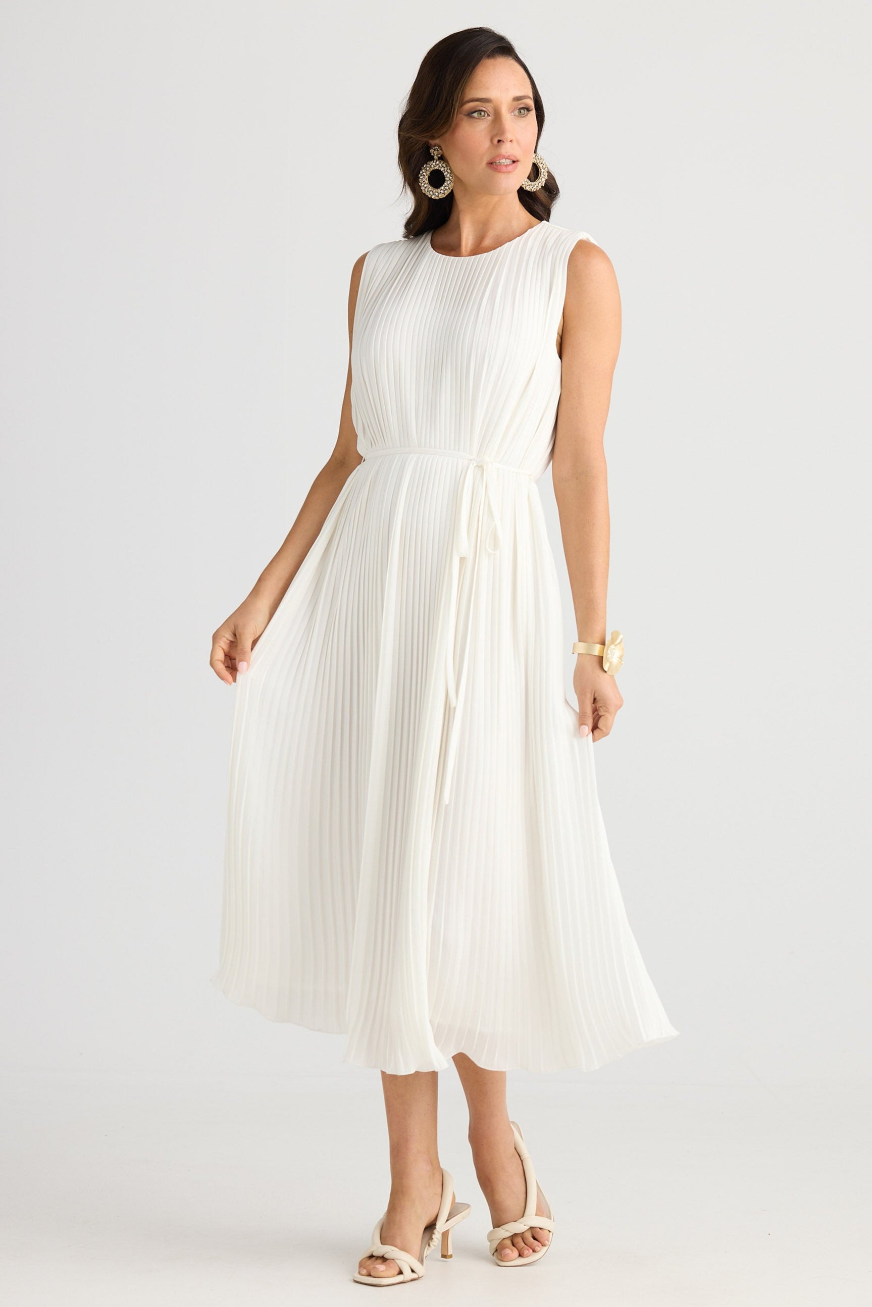 Woman wearing a white sleeveless dress on a plain background