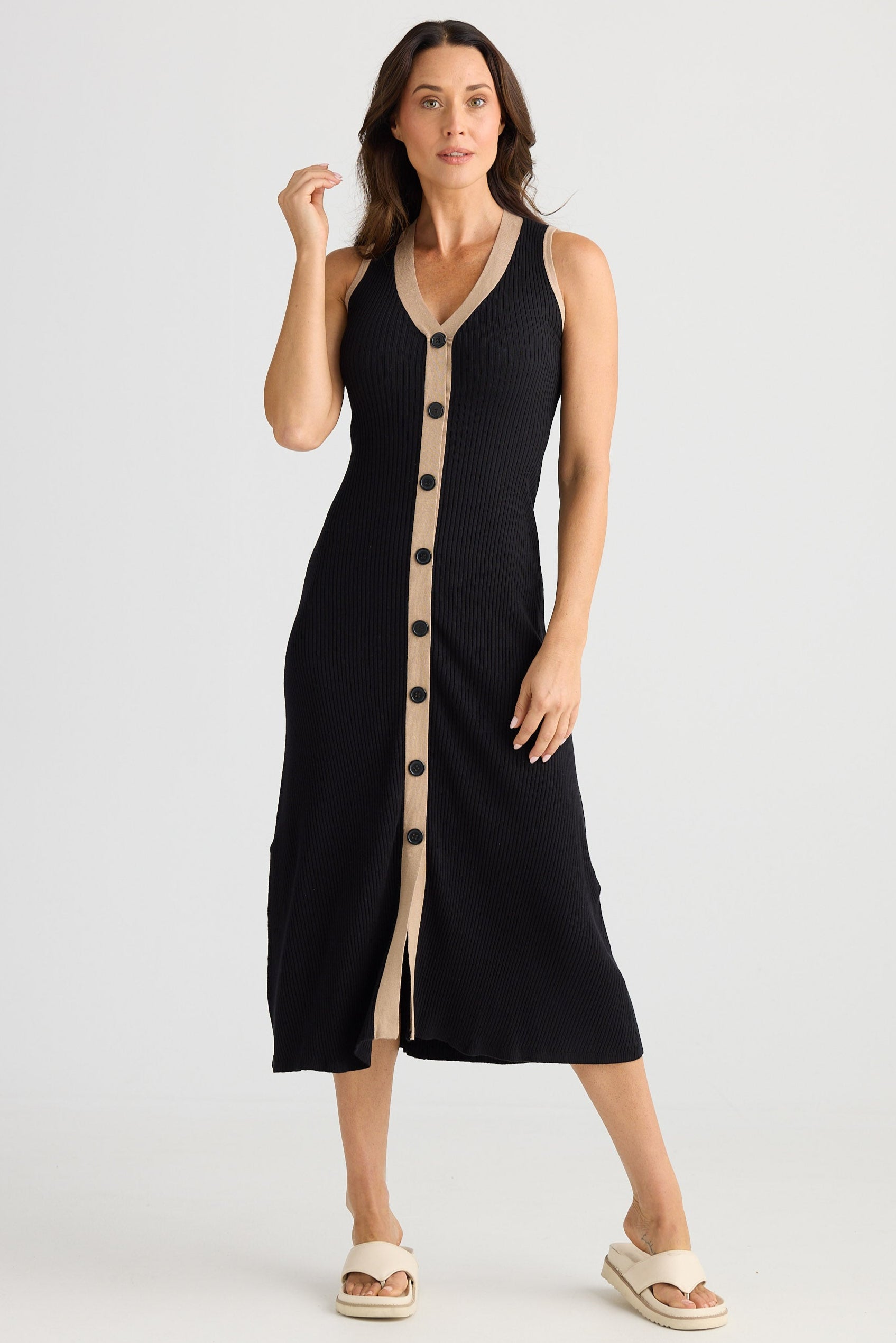 Woman wearing a black dress with beige buttons on a white background