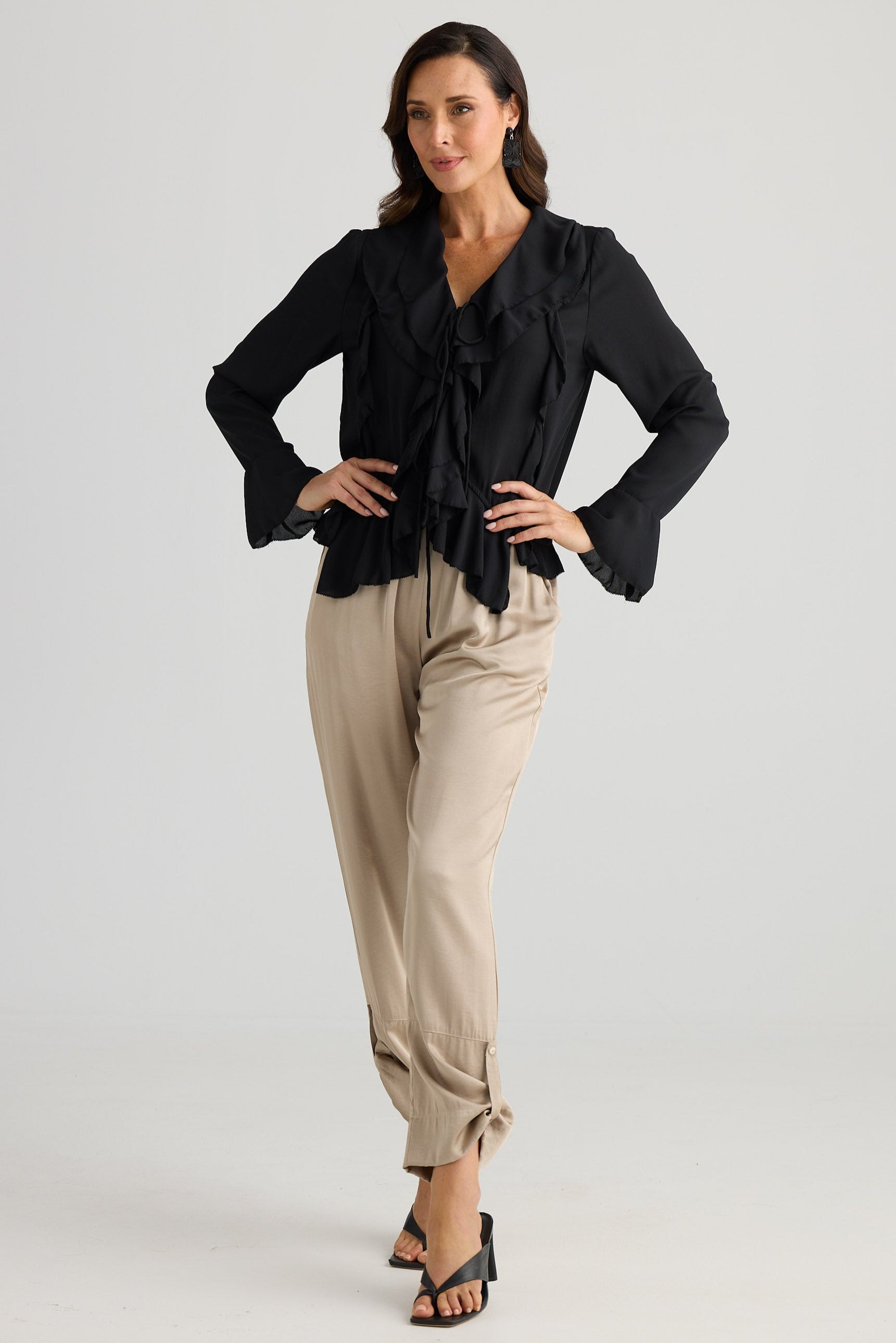 Woman wearing a black top and beige pants on a white background