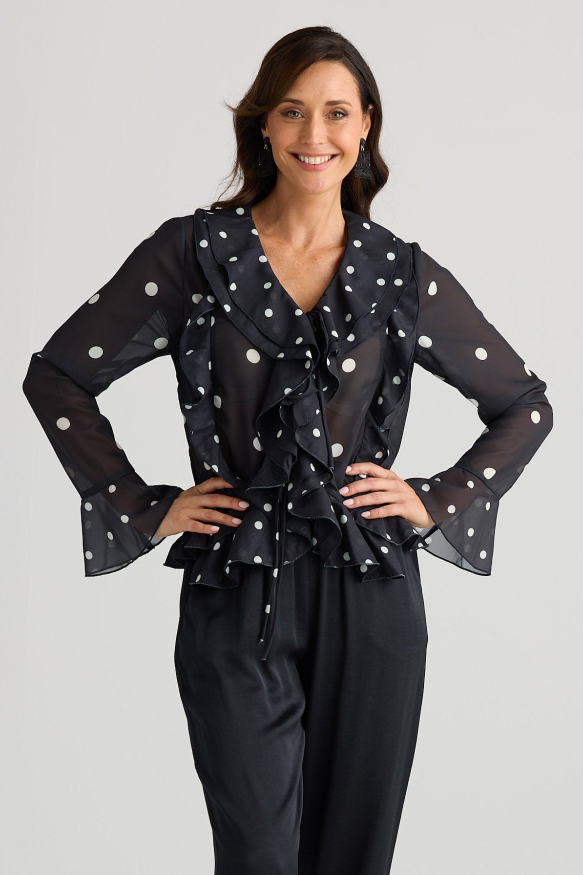 Woman wearing a black outfit with white polka dots on a plain background