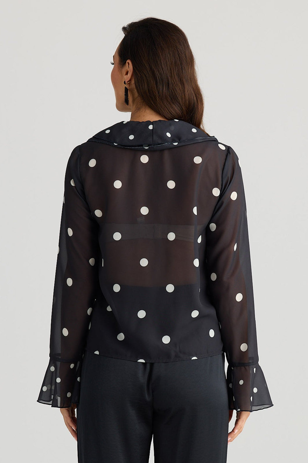 Woman wearing a black outfit with white polka dots on a white background