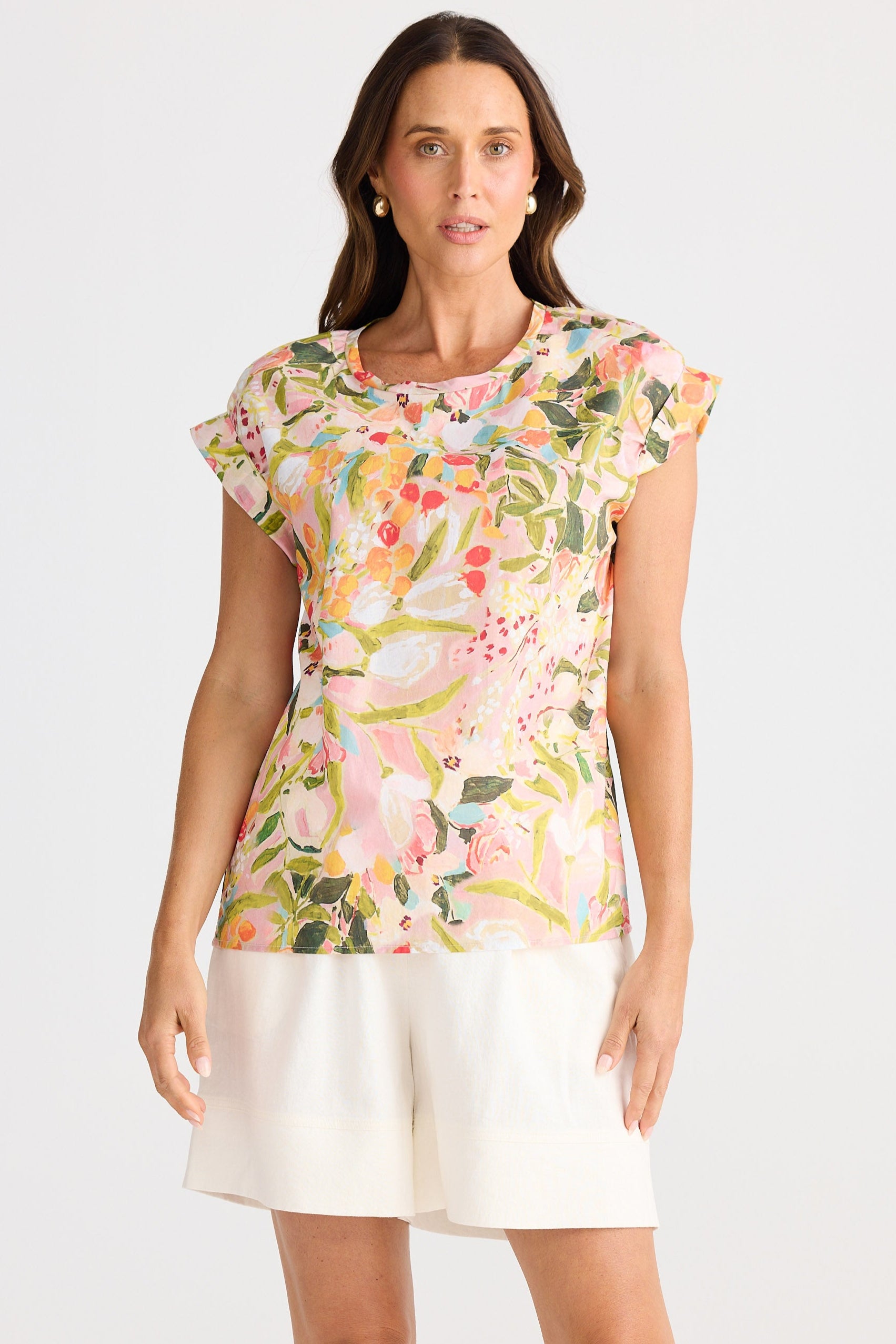 Woman wearing a floral top and white shorts on a light gray background