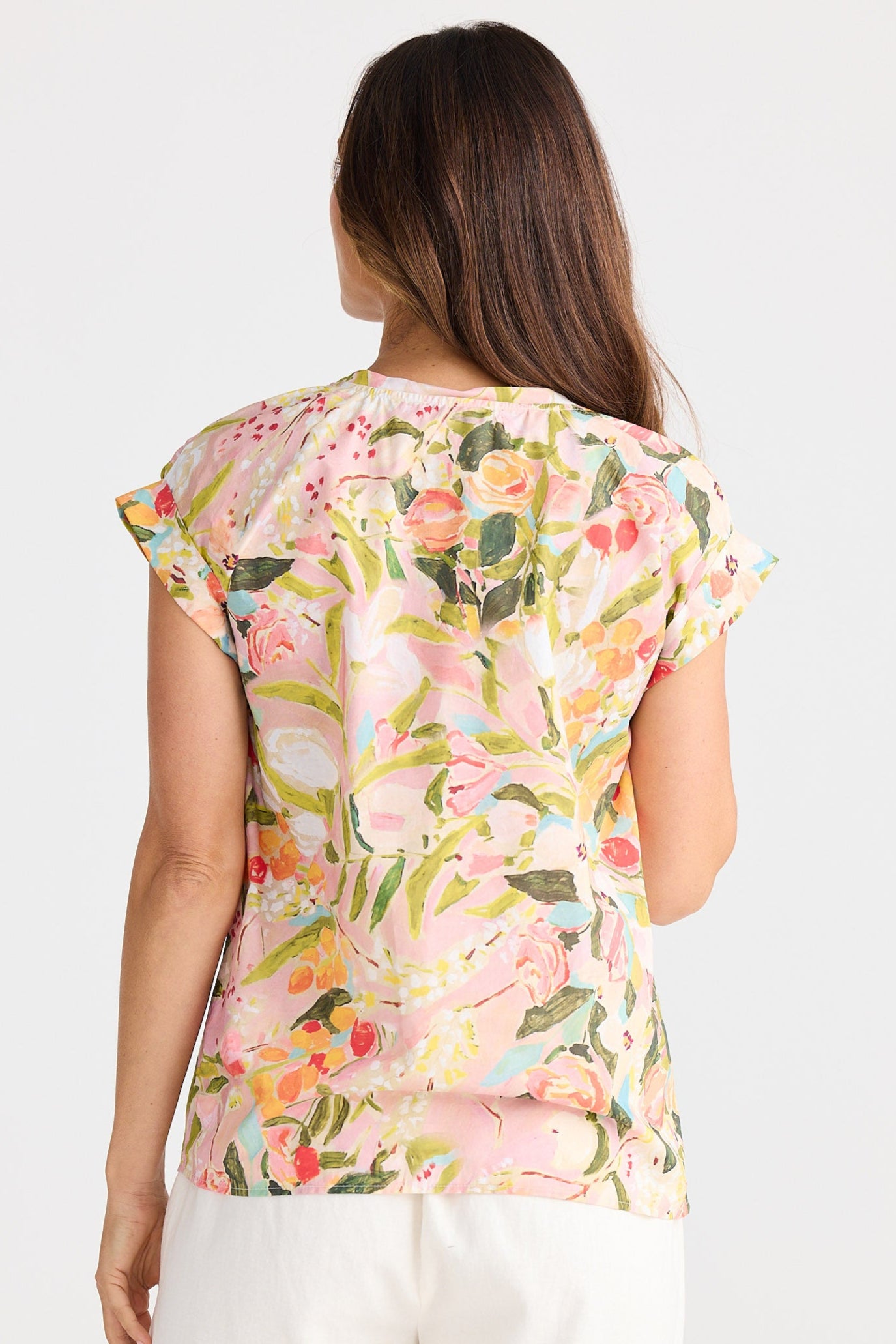 Woman wearing a floral top and white shorts on a plain background