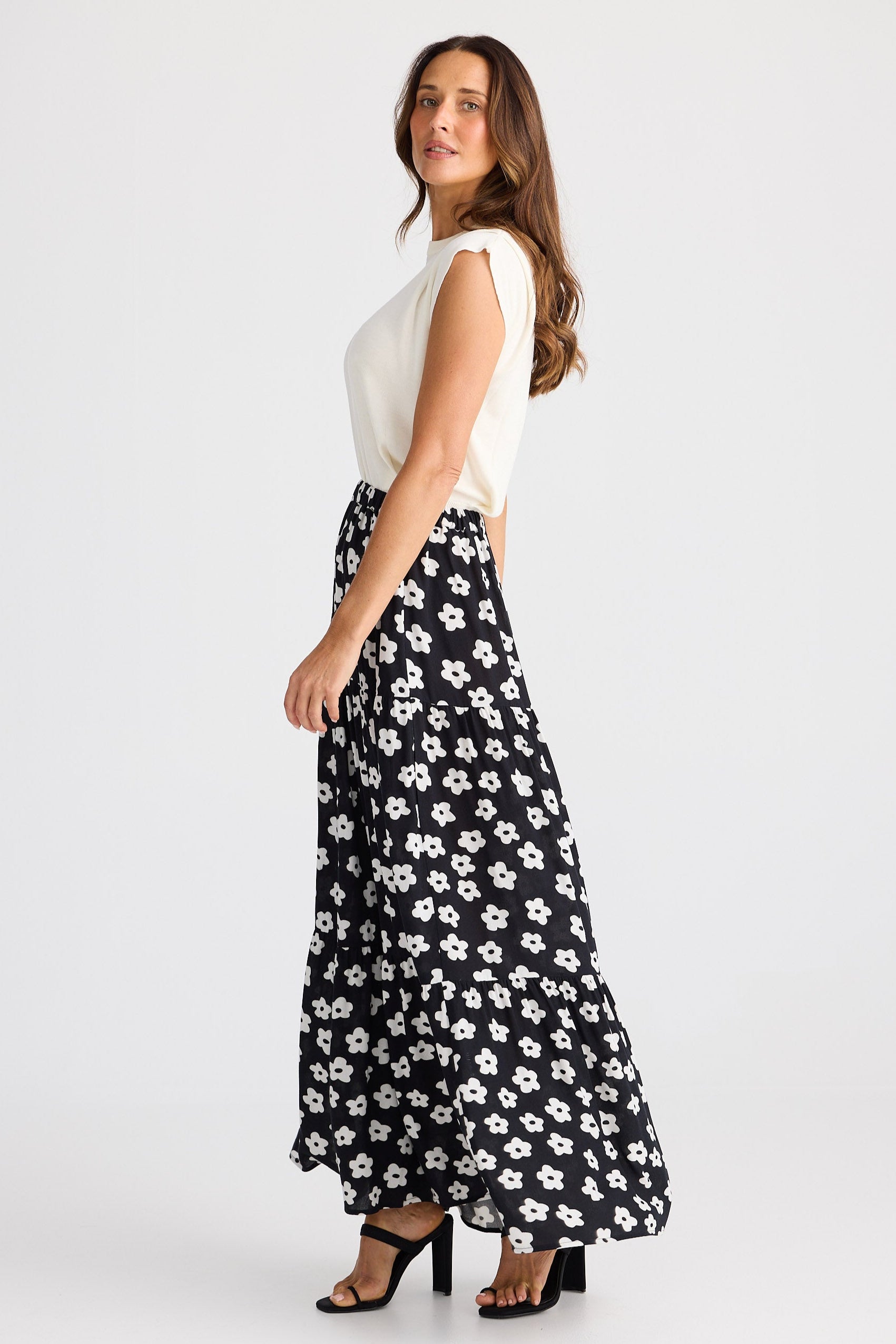 Woman wearing a white top and black floral skirt on a white background