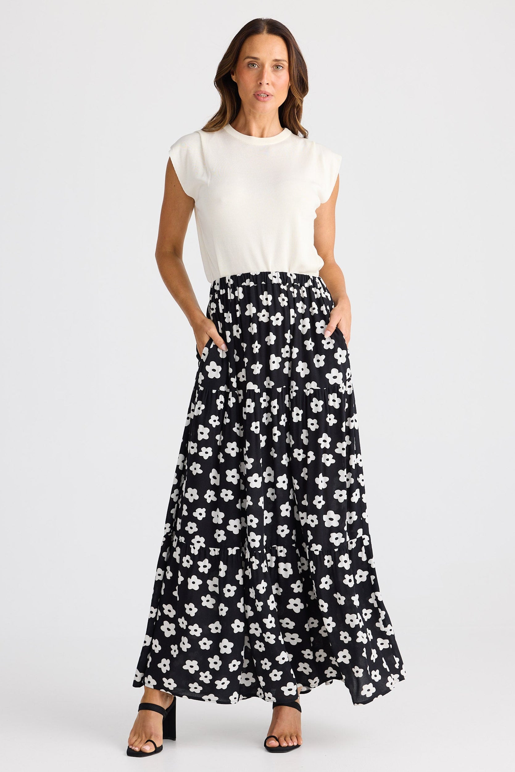 Woman wearing a white top and black floral skirt on a white background