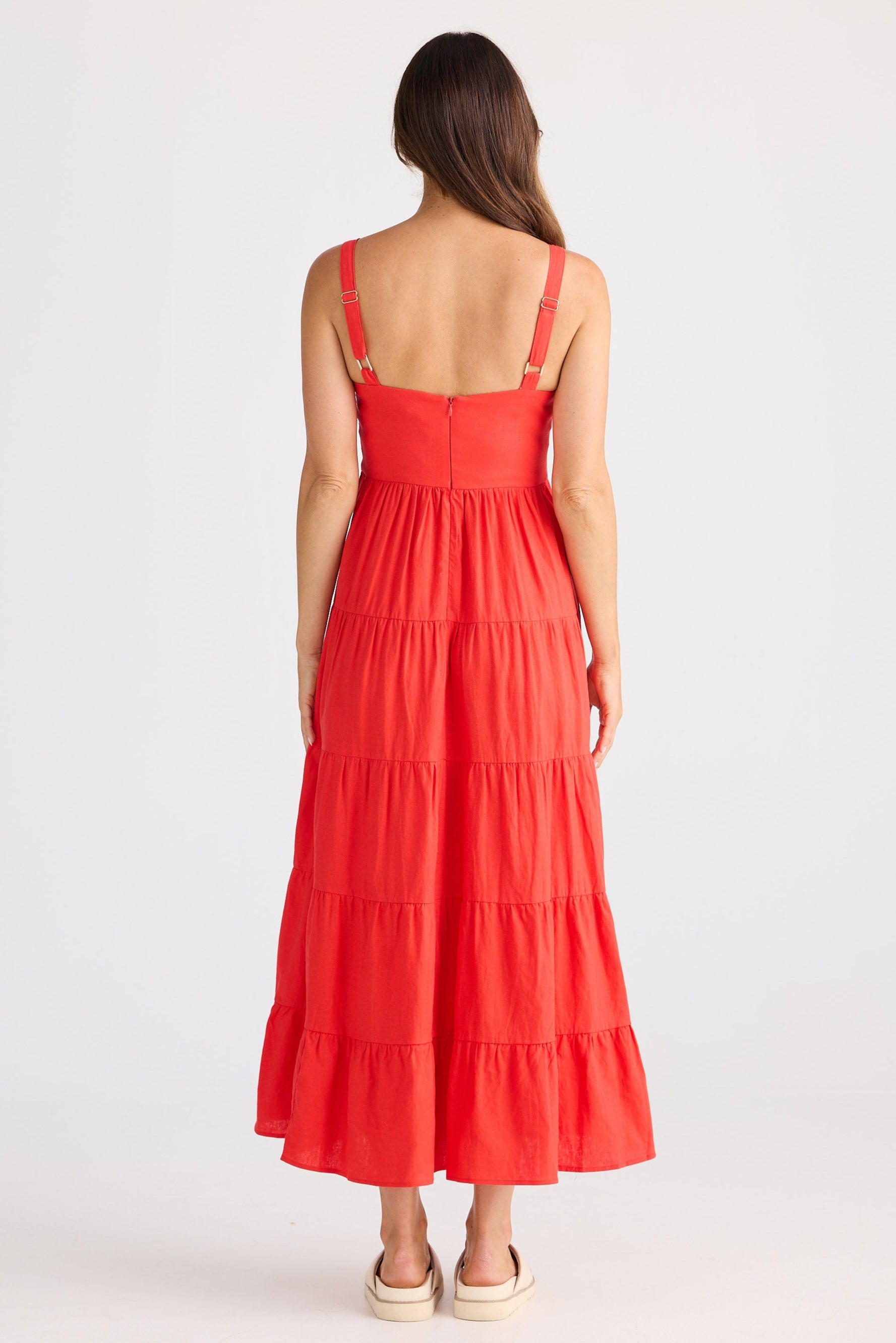 Woman wearing a red dress with tiered layers on a white background