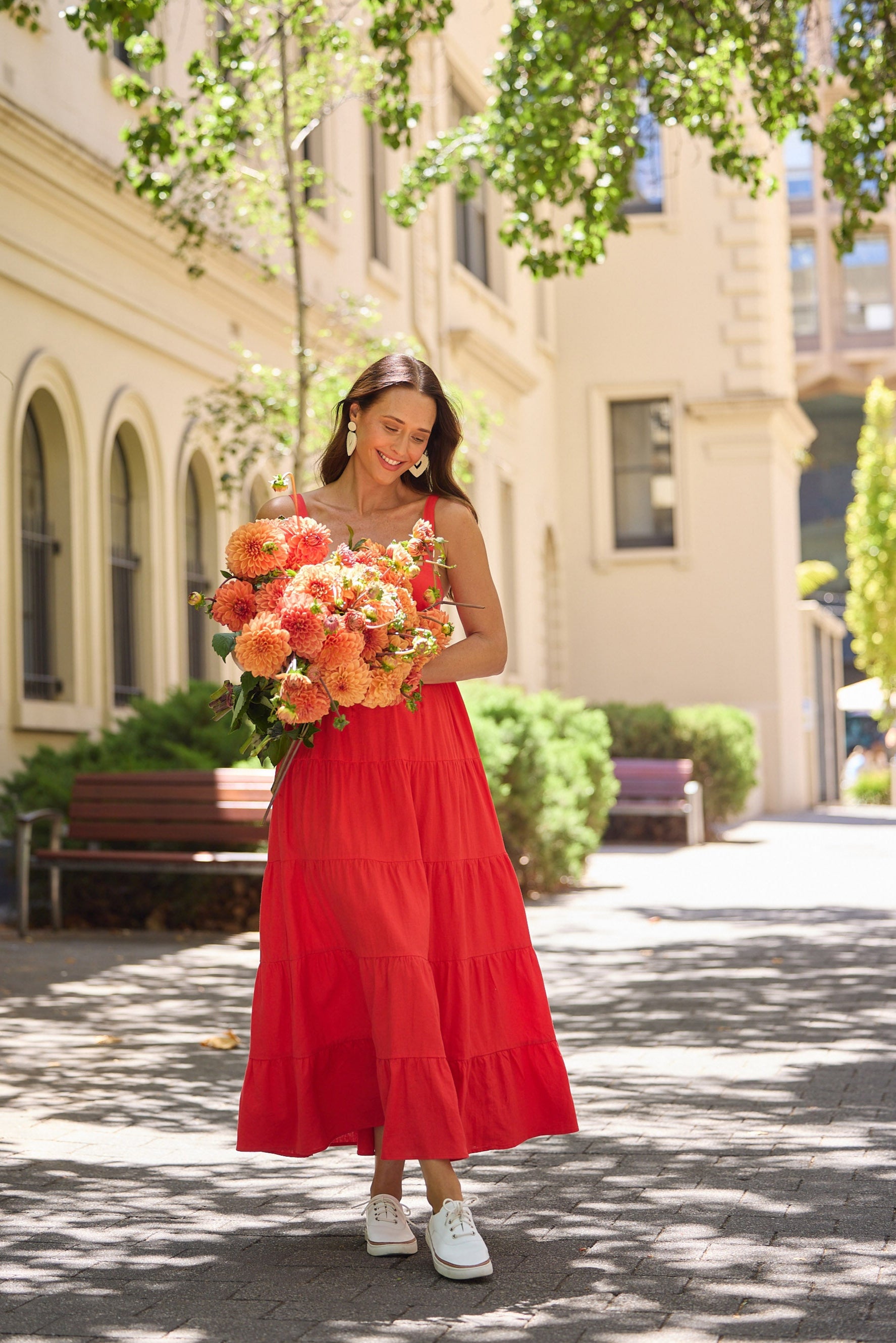 Woman in a red dress holding flowers in an urban setting