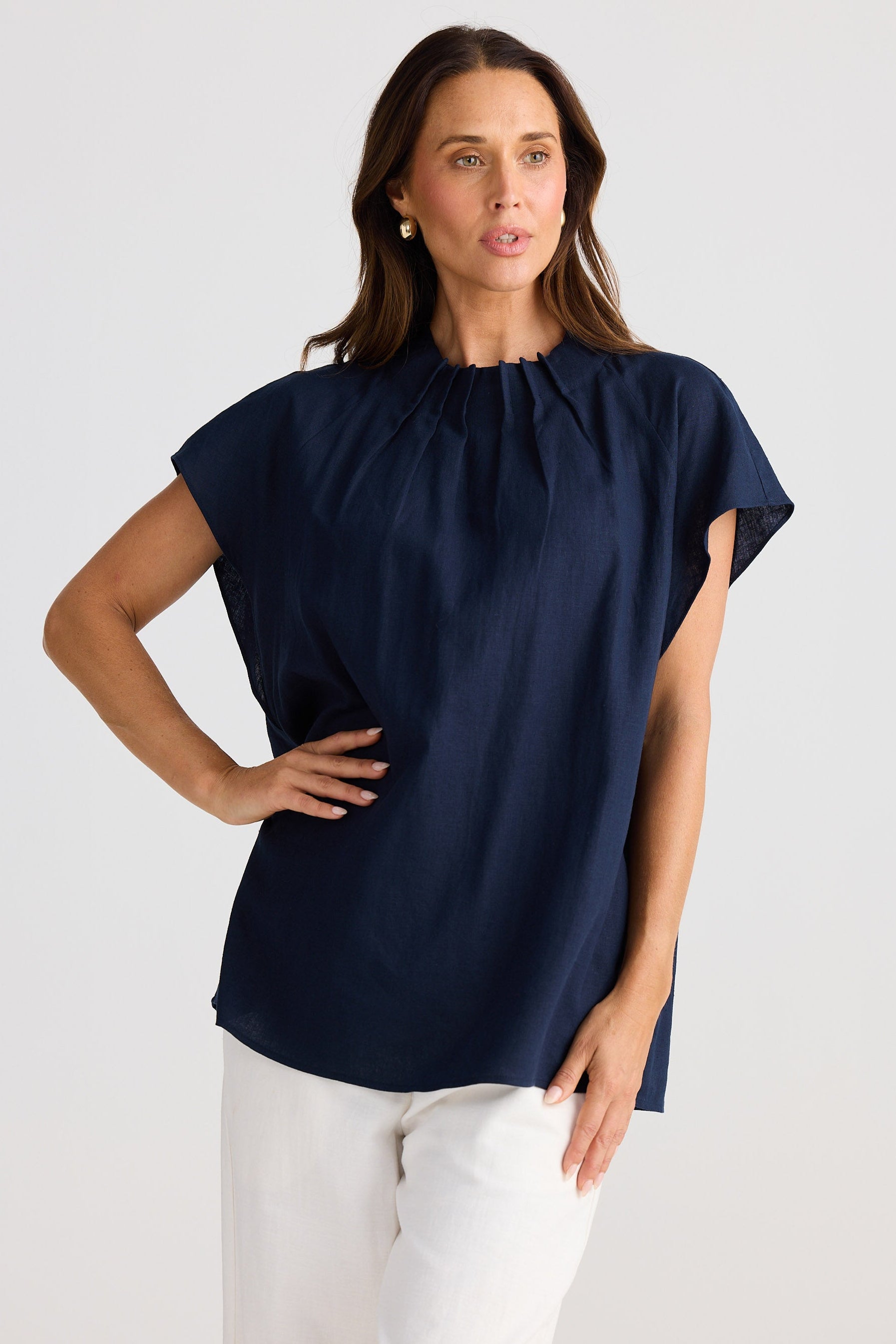 Woman wearing a navy blue top with a plain background