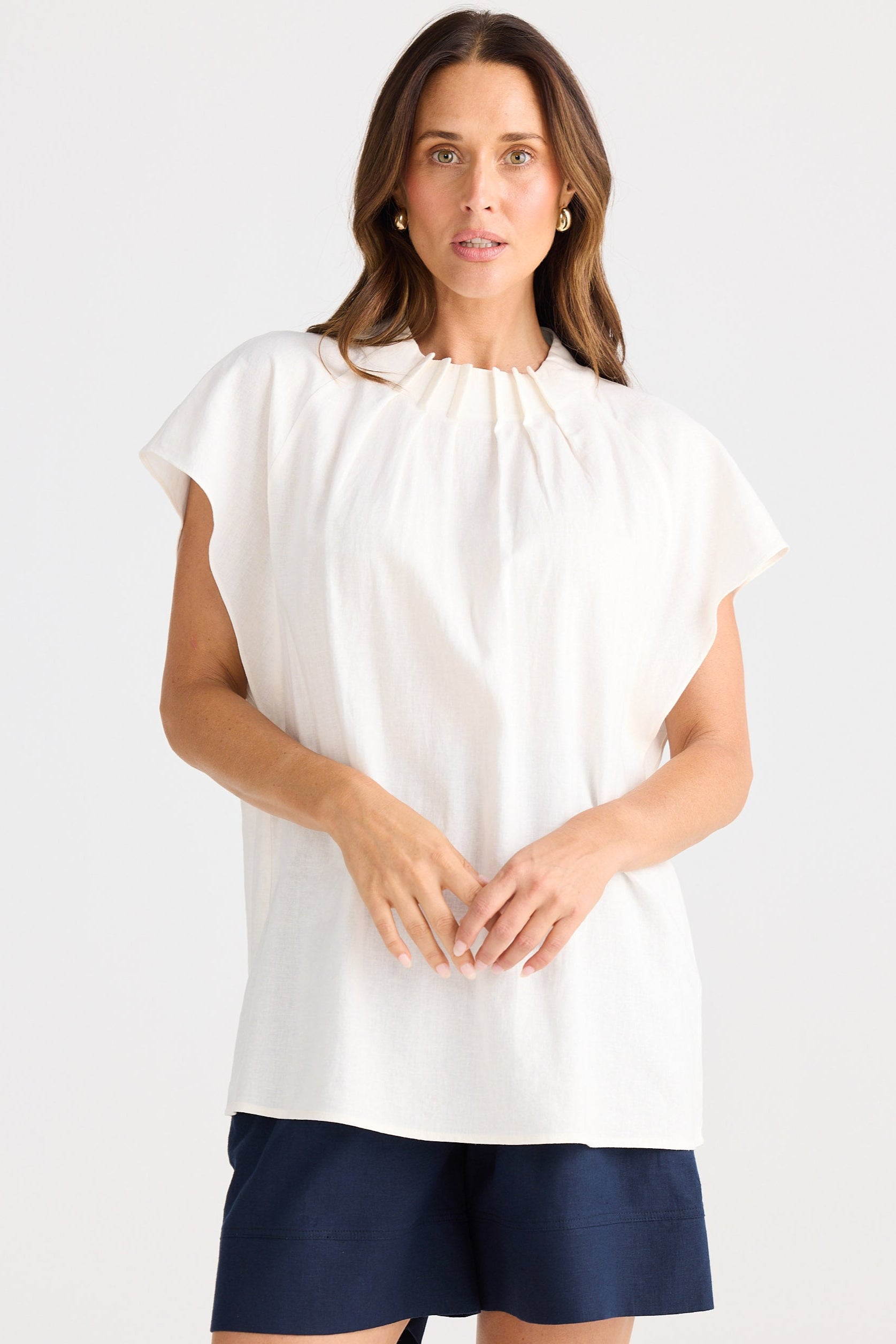 Woman wearing a white blouse and navy shorts on a white background