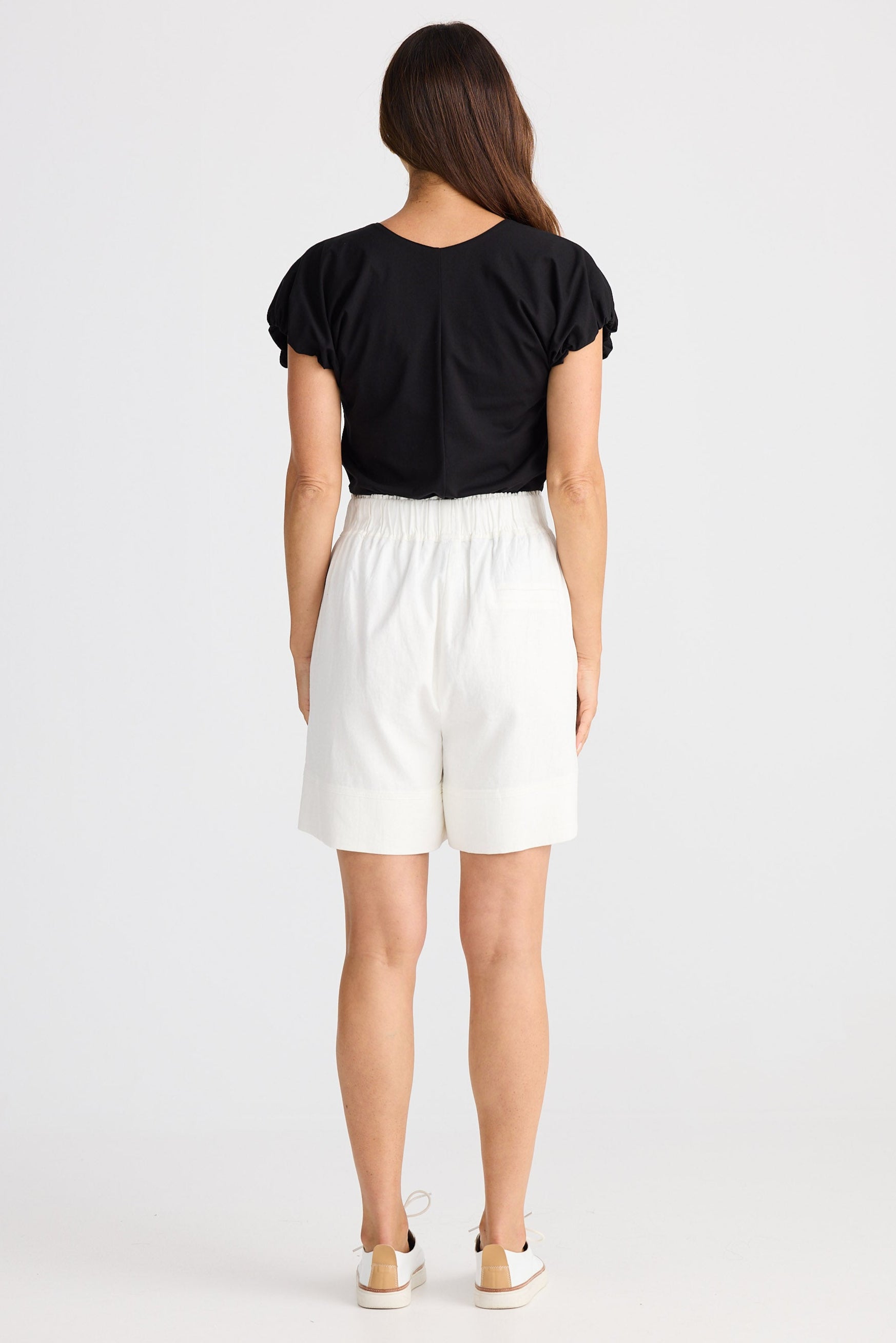 Person wearing a black top and white shorts on a white background