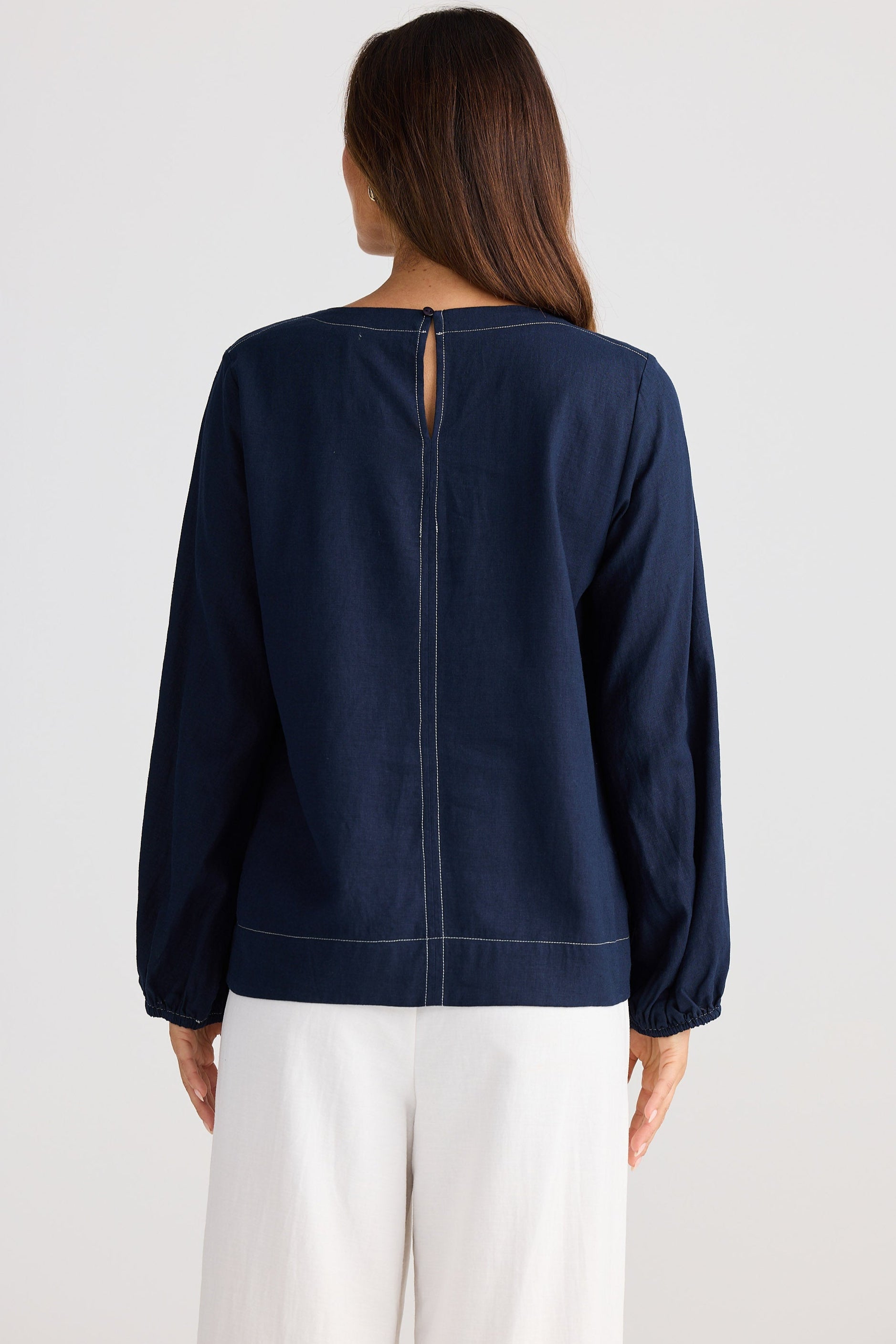 Navy blue long-sleeve top worn by a person on a white background