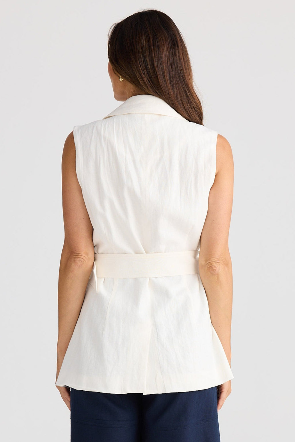 Woman wearing a white sleeveless top and navy shorts on a light gray background