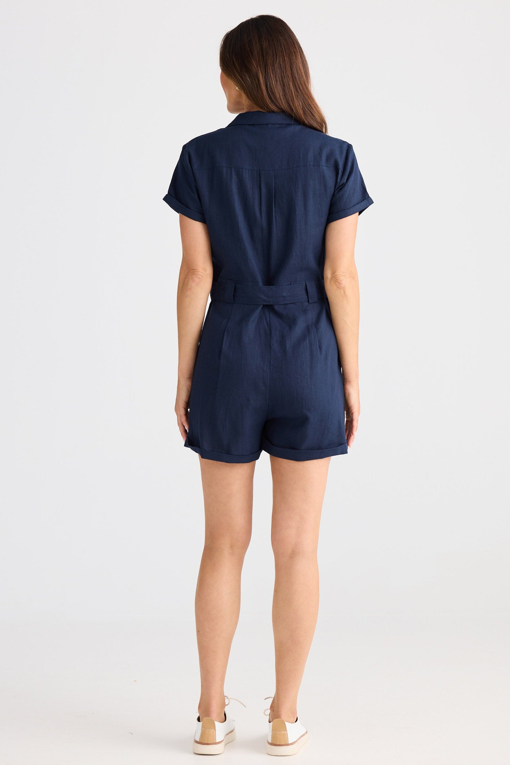 Woman wearing a navy blue romper on a white background