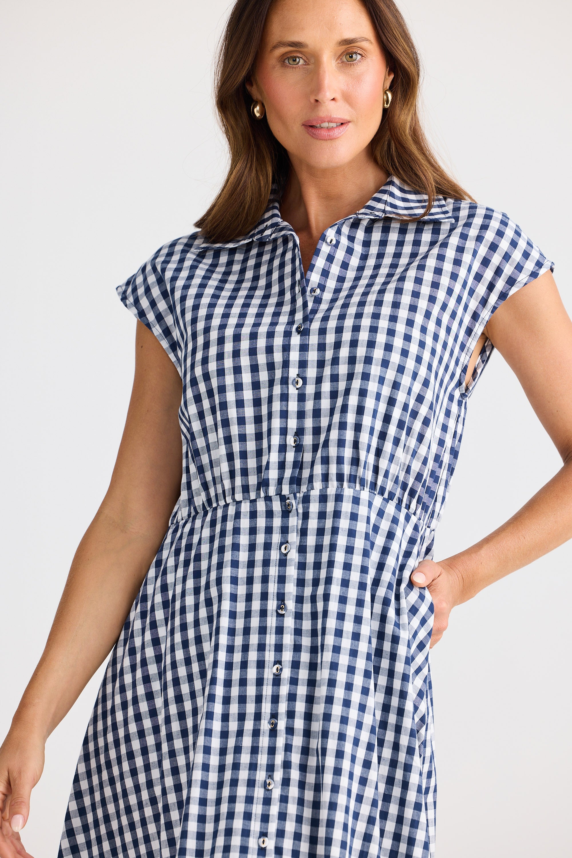 Woman wearing a blue and white checkered dress against a plain background