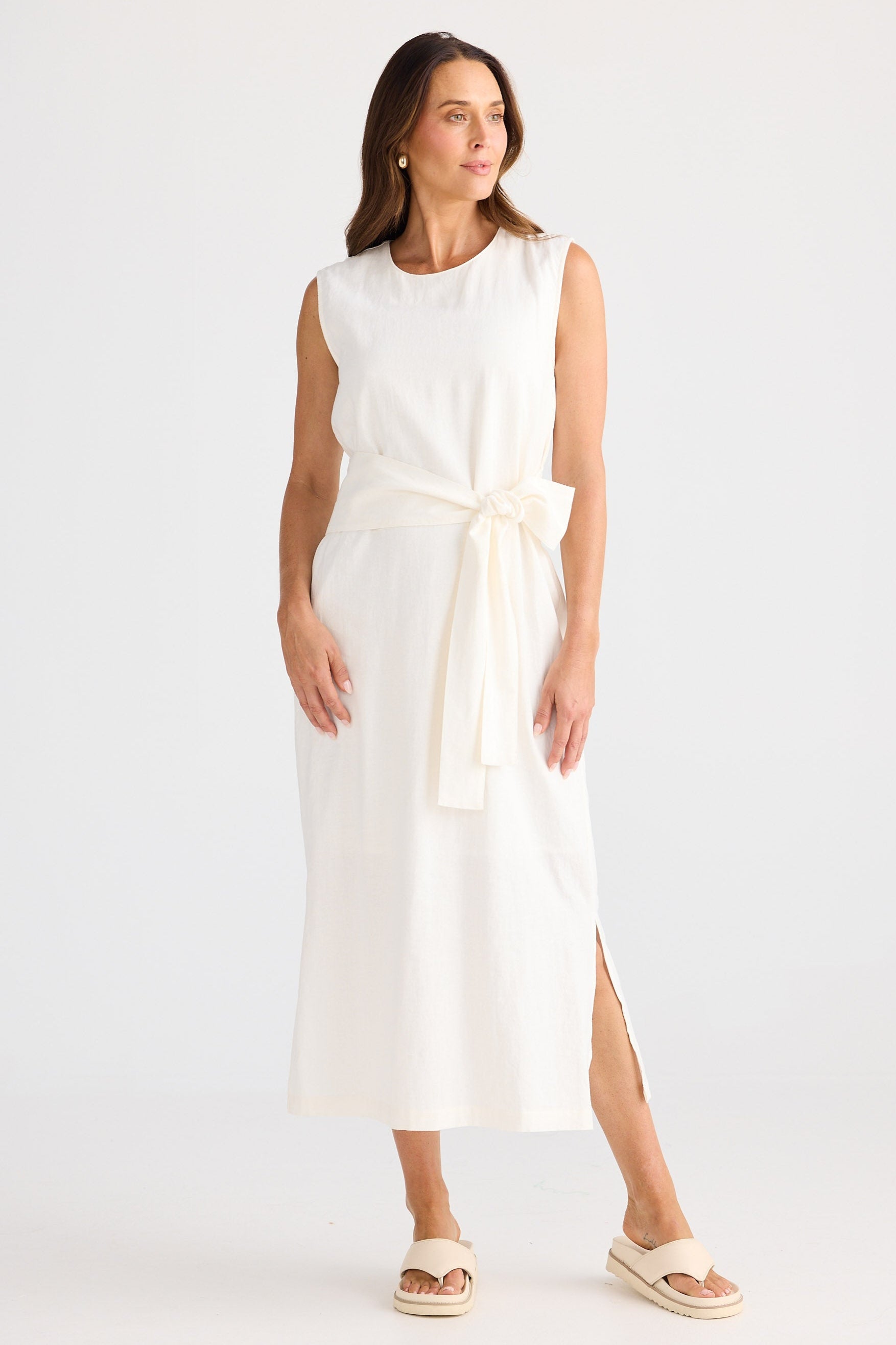 Woman wearing a white sleeveless dress with a belt on a white background