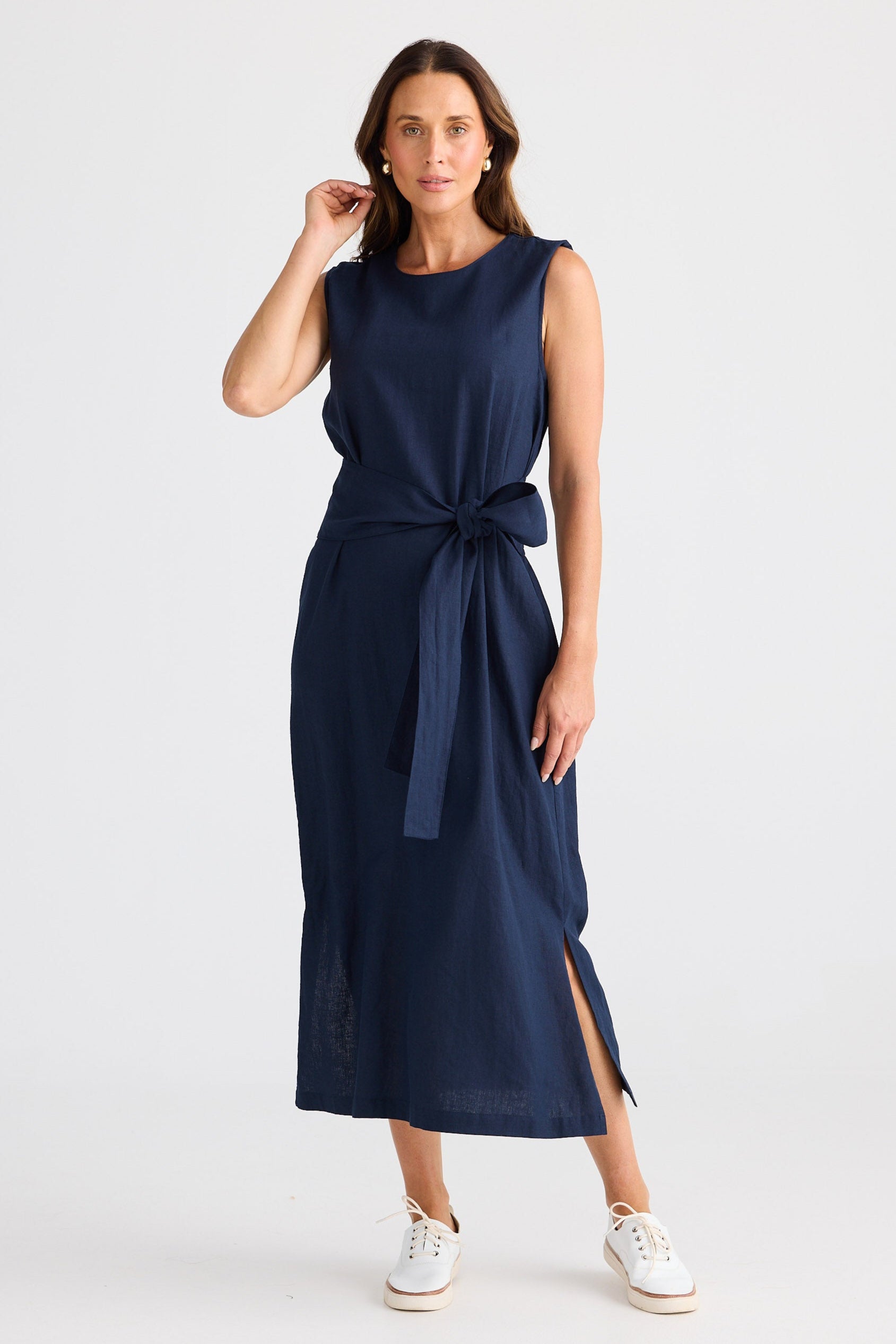 Woman wearing a navy blue dress with a tie waist on a white background