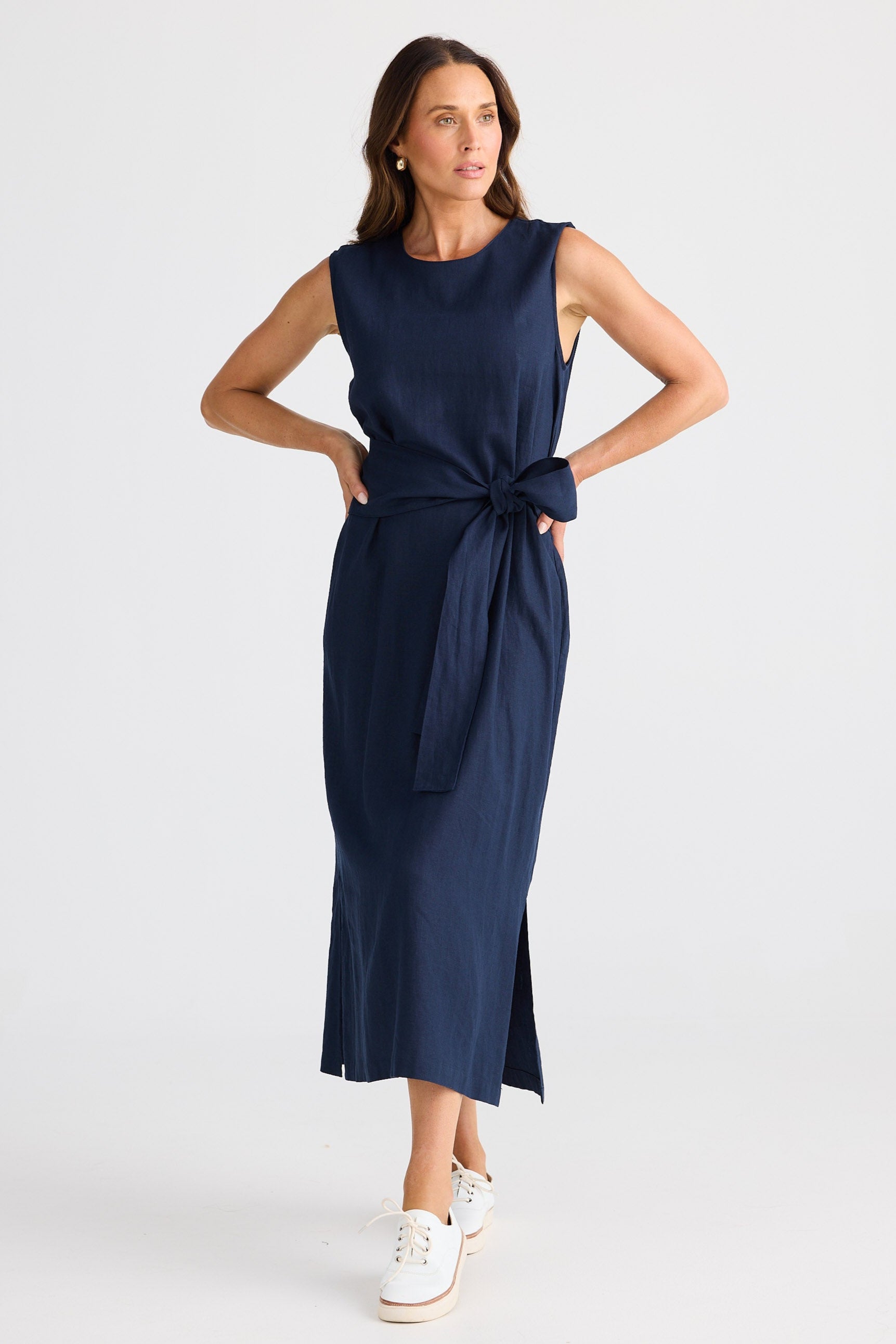Woman wearing a navy sleeveless dress with a knot detail on a white background