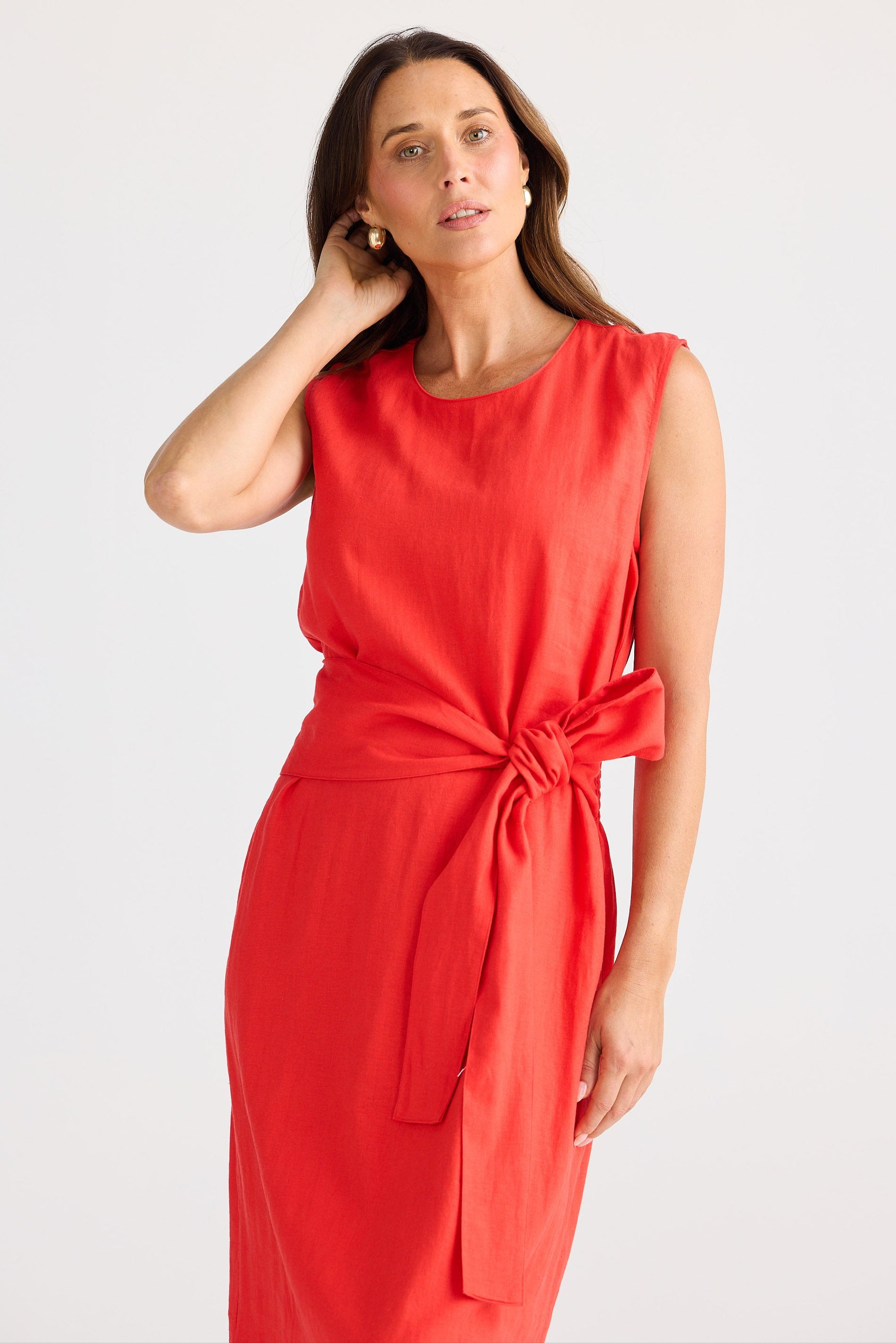 Woman wearing a red dress with a tie detail on a white background