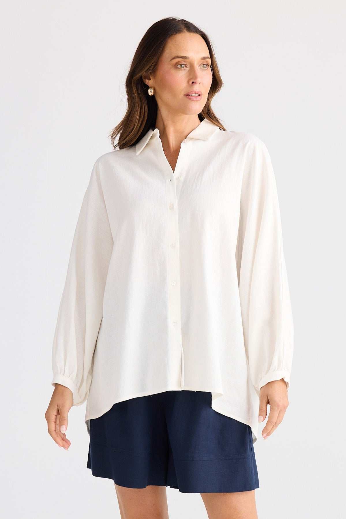 Woman wearing a white shirt and navy shorts on a white background